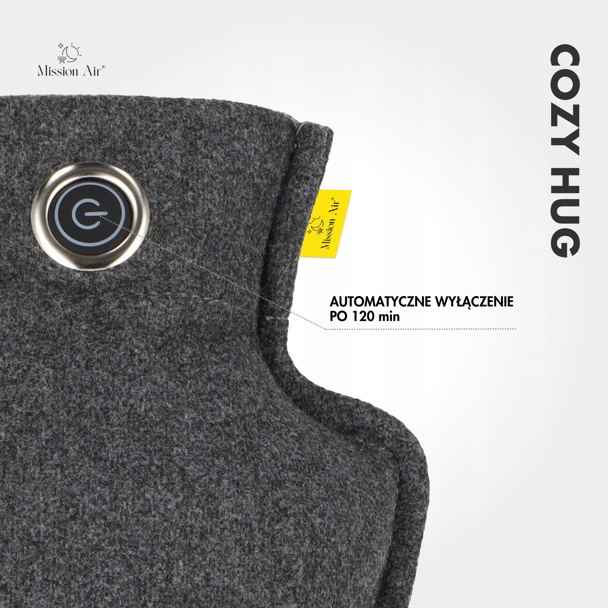 Zbliżenie szarego materiału z przyciskiem zasilania. Żółta etykieta z tekstem. Słowo COZY HUG po prawej.