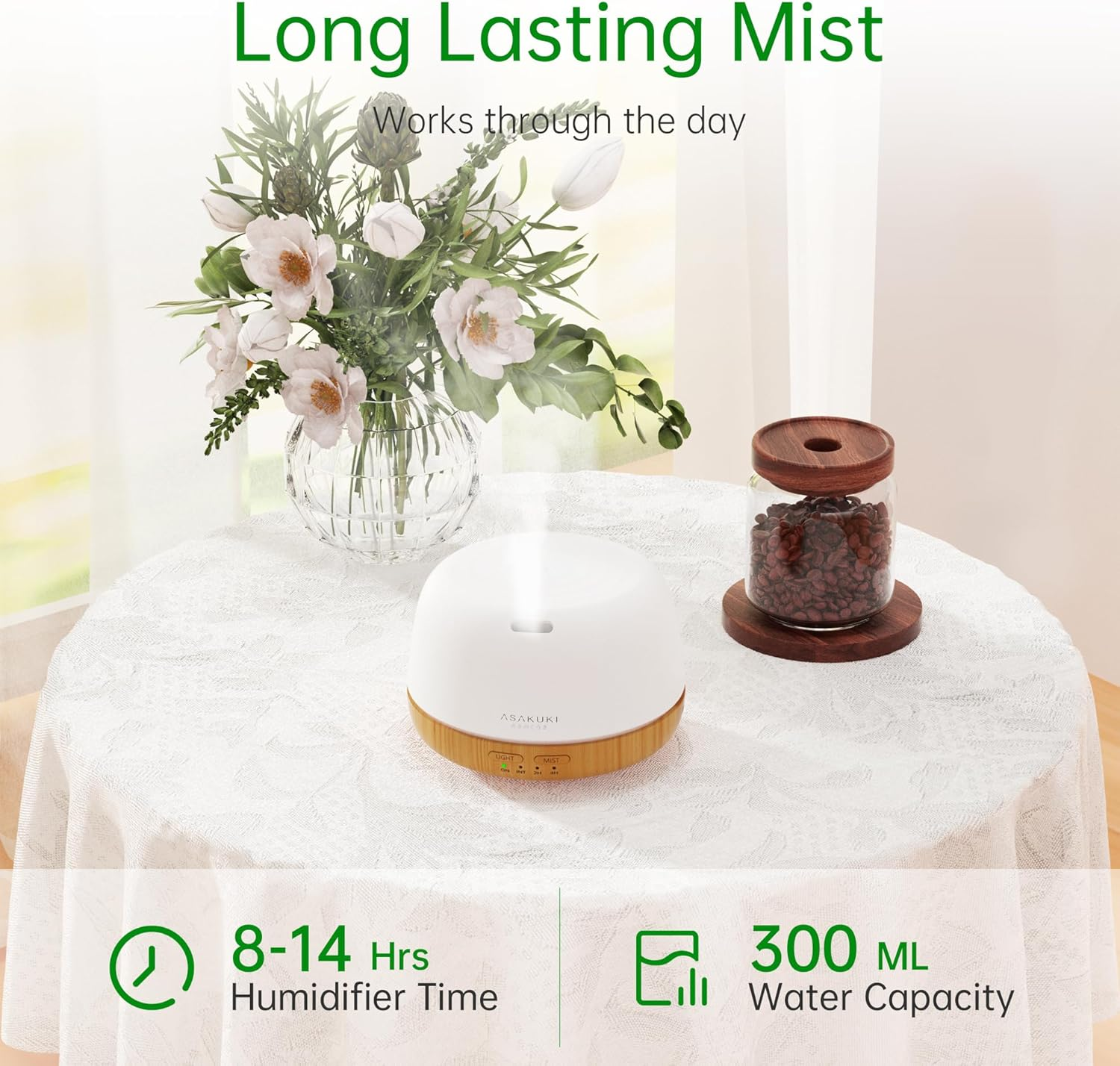 Ein weißer Diffusor mit Nebel, Blumen in einer Vase und ein Glas Bohnen auf einem Tisch. Text: Long Lasting Mist, 8-14 Std., 300 ml.