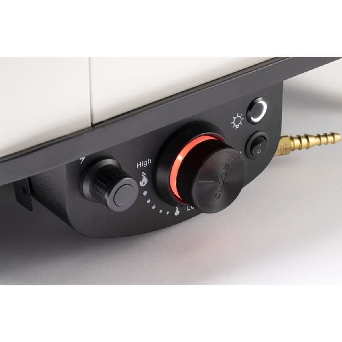 Close-up van een bedieningspaneel van een grill. Knoppen en knoppen met een rood verlichte draaiknop. Een messing gasleiding loopt vanaf de zijkant.