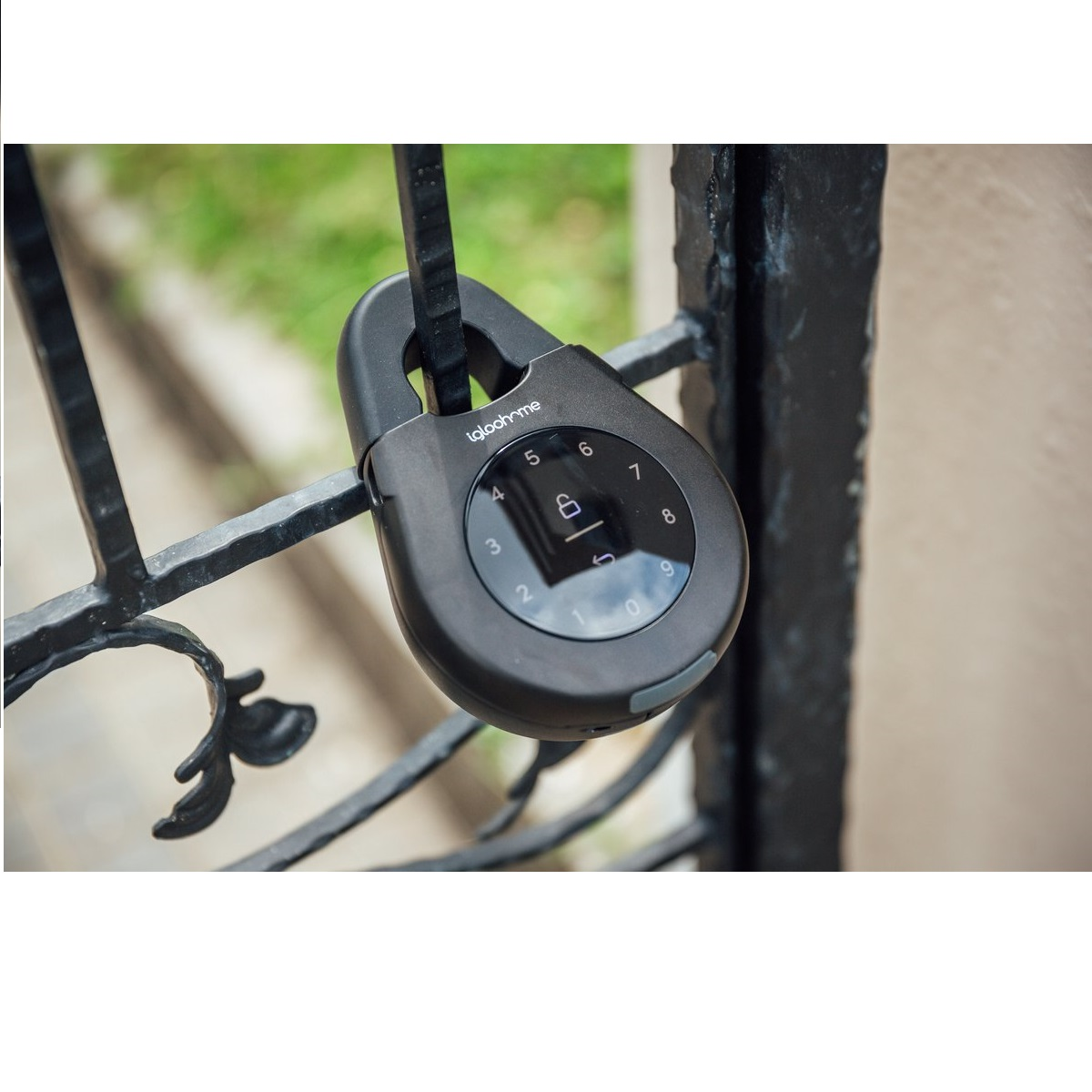 Ein schwarzes Vorhängeschloss mit digitaler Tastatur ist an einem schwarzen Metalltor verschlossen. Der Hintergrund ist verschwommenes grünes Laub.