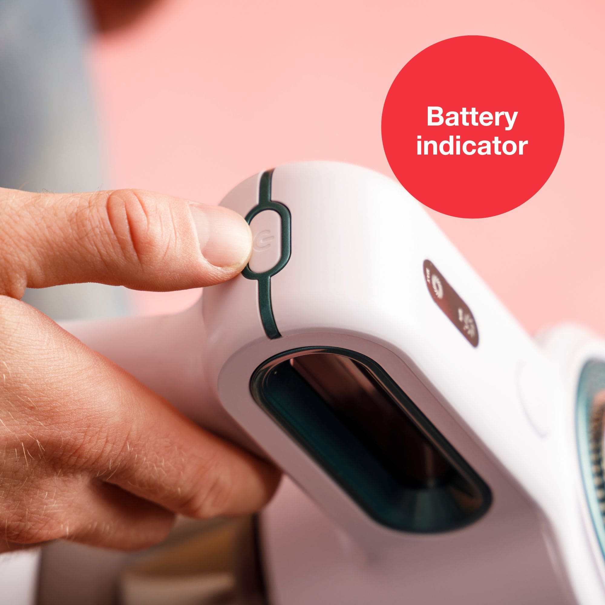 Eine Hand drückt einen weißen Knopf auf einem weiß-türkisfarbenen Gerät. Ein roter Kreis zeigt 'Batterieanzeige'.