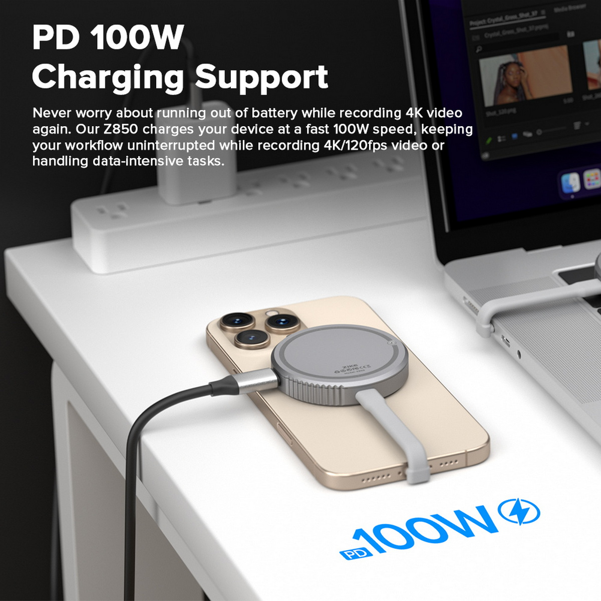 Ein Telefon, das mit einem grauen Ladegerät aufgeladen wird, ein Laptop und eine Steckdosenleiste befinden sich auf einem weißen Schreibtisch. Text: PD 100W Charging Support.