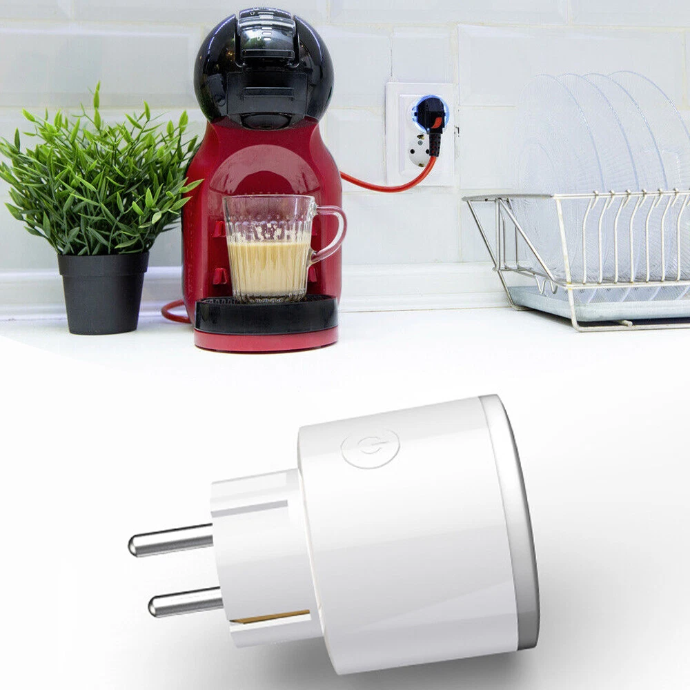 Eine rote Kaffeemaschine, ein Glas Kaffee, eine Pflanze in einem schwarzen Topf, ein weißer Stecker und ein Geschirrkorb mit Tellern.