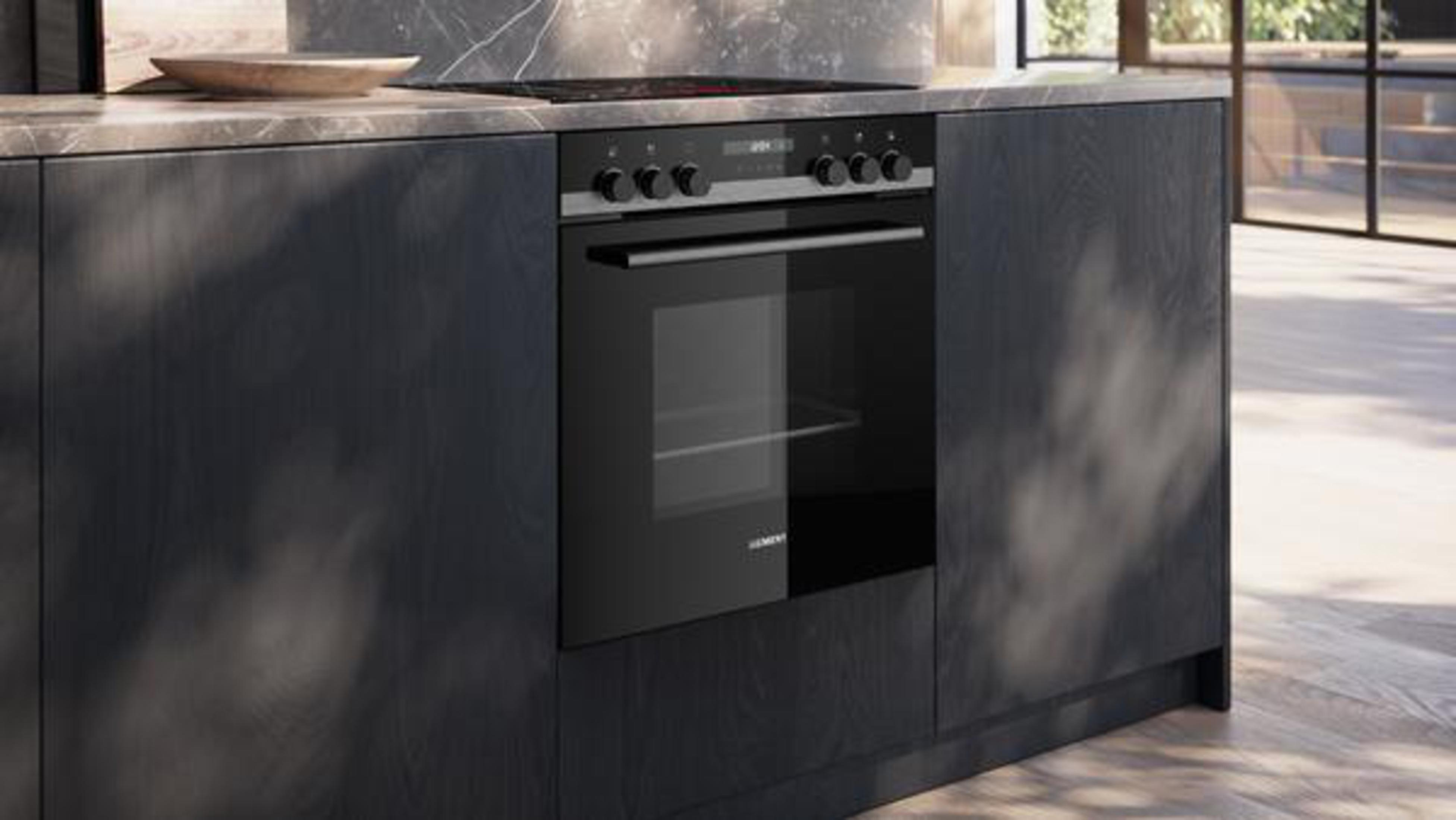 Moderne Küche mit schwarzem Backofen und Kochfeld. Eine Holzschale steht auf der Arbeitsplatte.