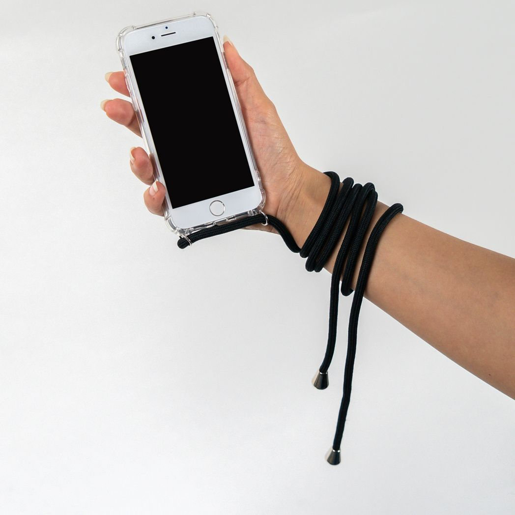 Une main tient un téléphone à écran noir. Un cordon noir s'enroule autour du poignet. Fond blanc.