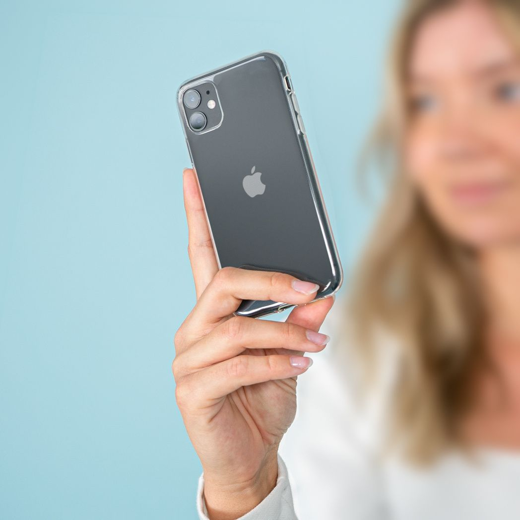 Una mujer sostiene un iPhone gris oscuro con una funda transparente. El fondo es azul claro.