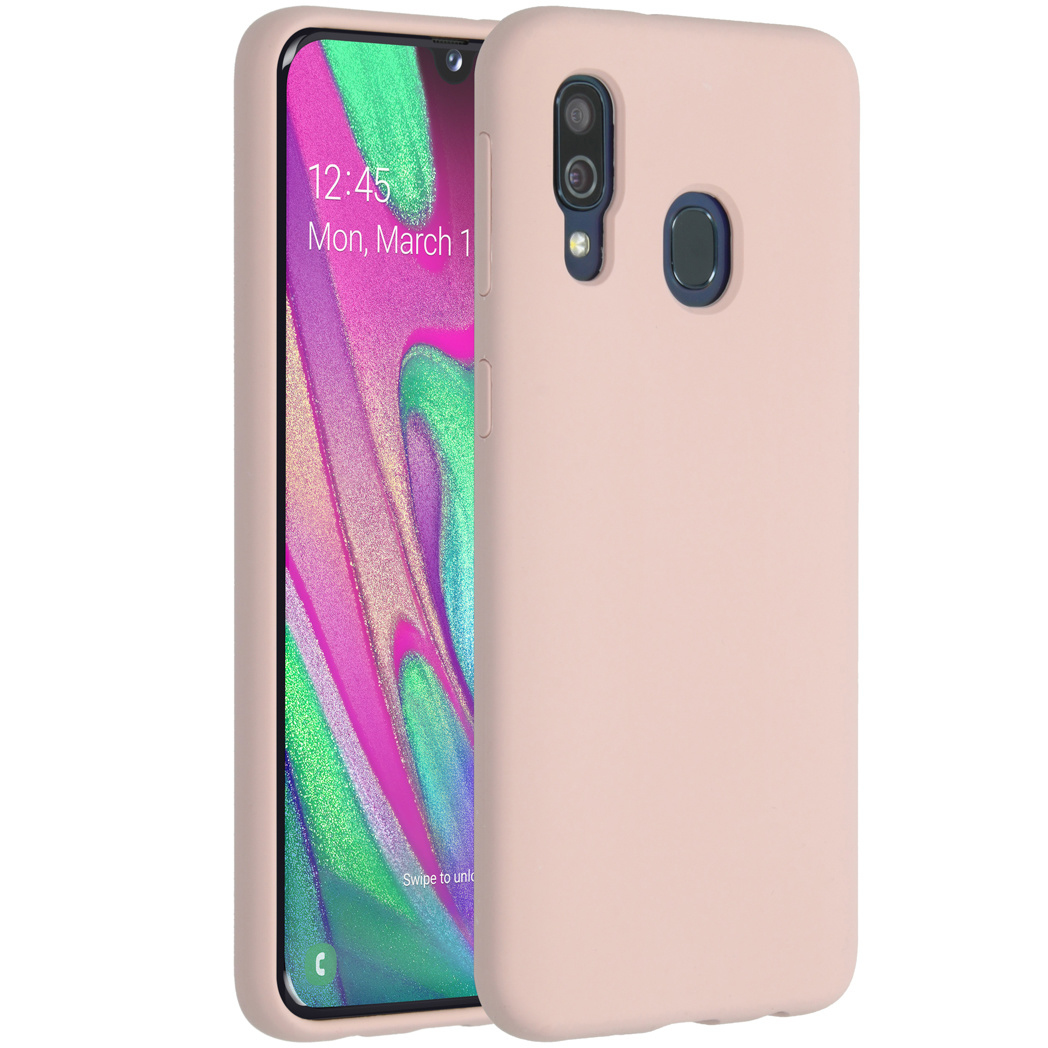Un téléphone rose avec un étui. L'écran affiche l'heure, la date et un fond abstrait coloré. L'étui possède une caméra.