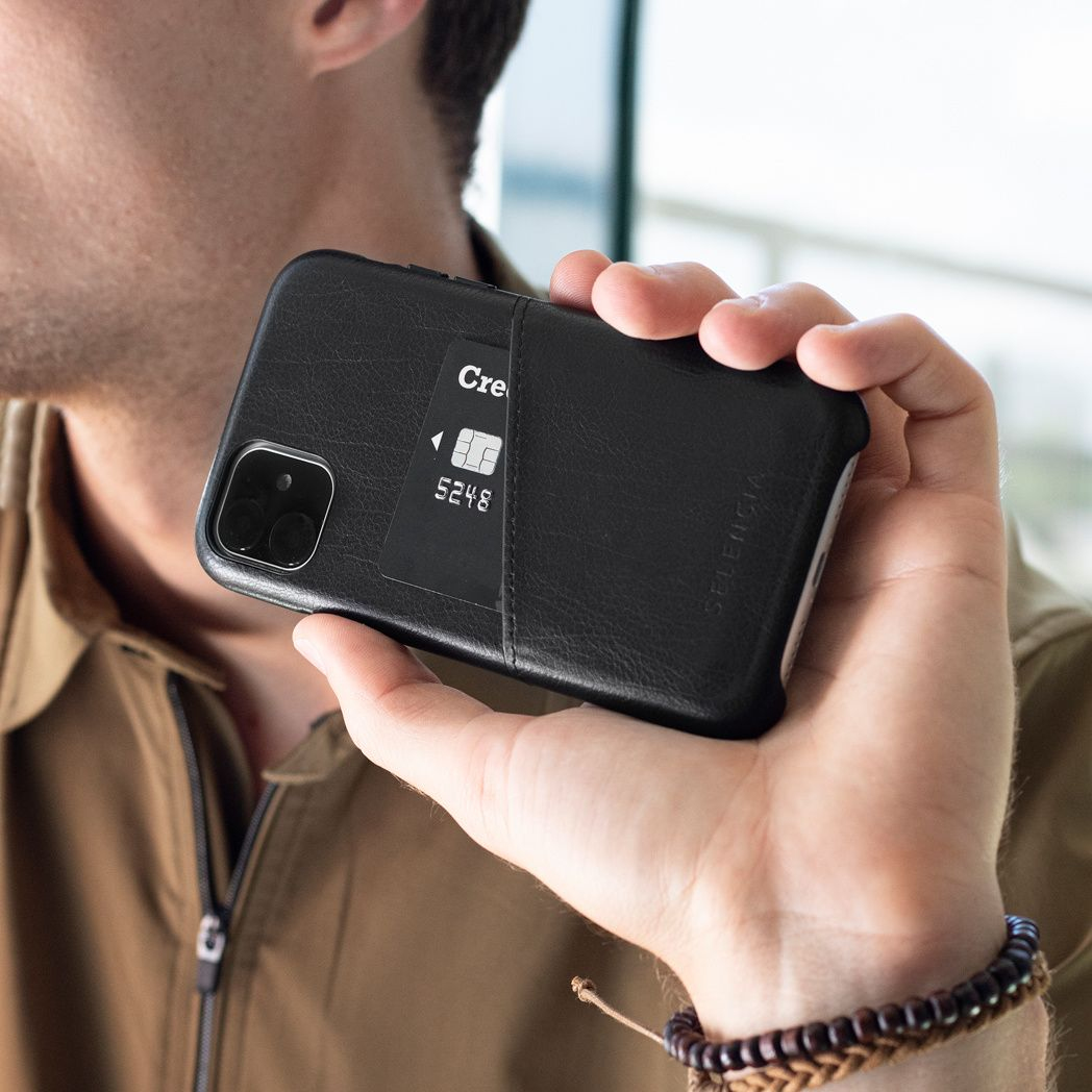 Une personne tient un étui de téléphone noir avec une carte de crédit visible. L'étui a un logo, la carte des chiffres et un logo.