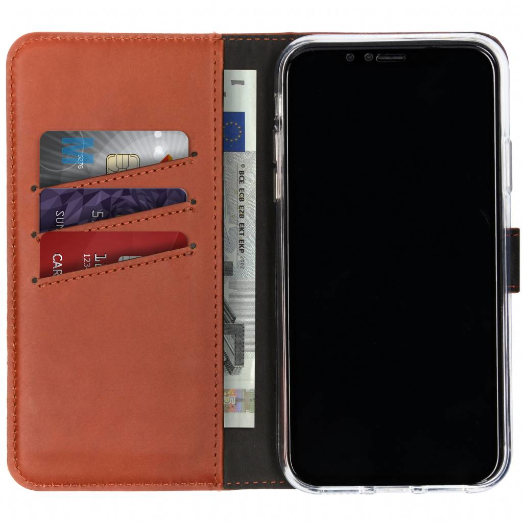Een bruine leren portemonnee bevat kaarten en een eurobiljet. Een smartphone staat aan de rechterkant van de portemonnee.