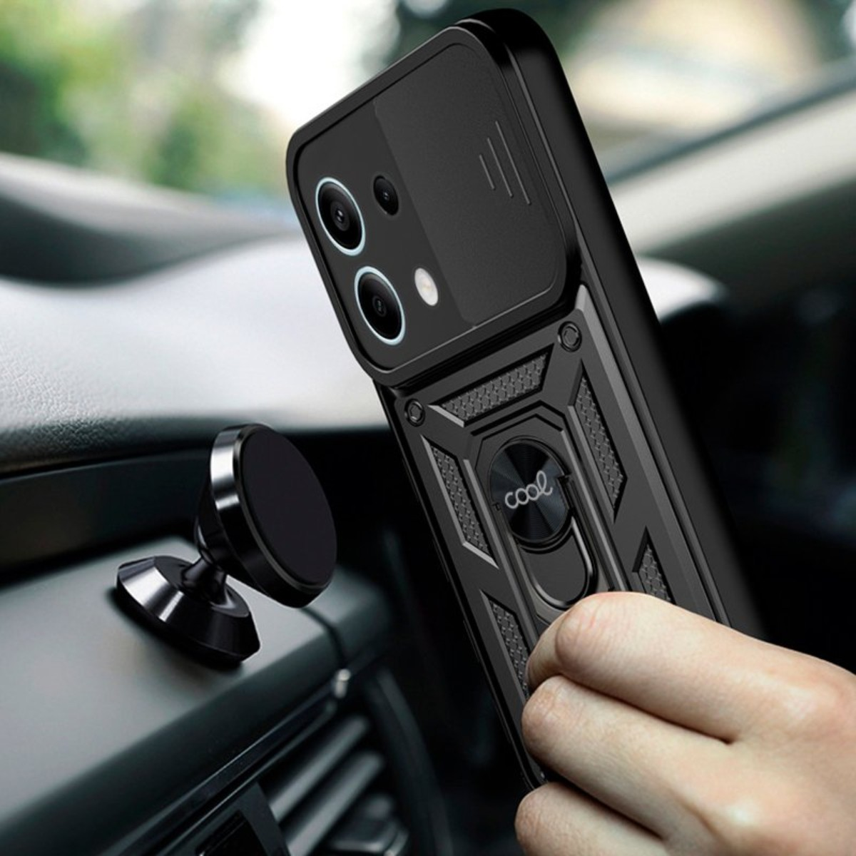 Una custodia nera per telefono con supporto ad anello viene tenuta in un'auto. Un supporto magnetico è sul cruscotto.