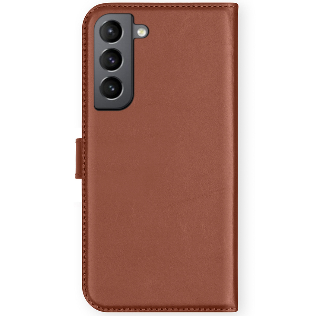 Una custodia per telefono in pelle marrone. Ha un ritaglio per la fotocamera, una chiusura a bottone e un bordo cucito. Lo sfondo è bianco.