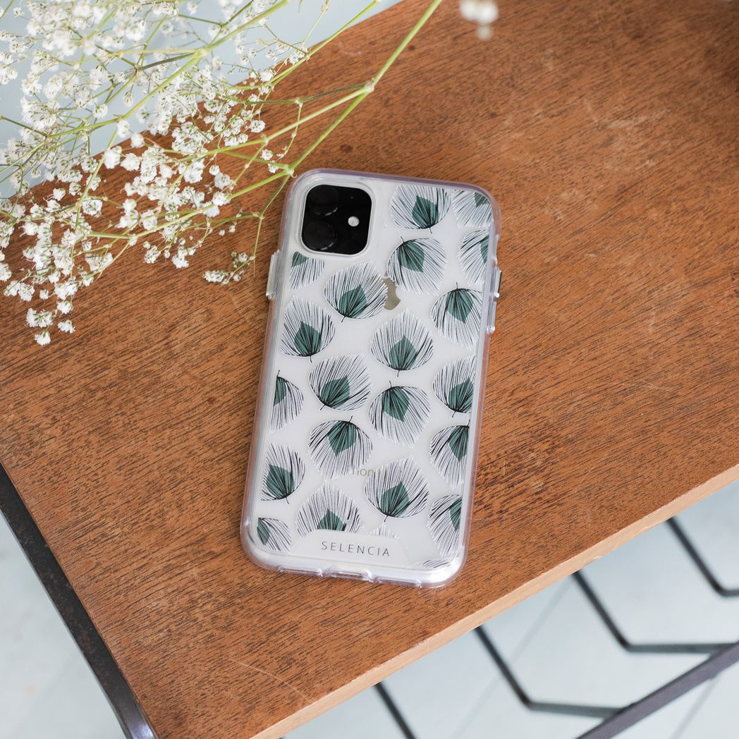 Téléphone avec étui à motifs sur une surface en bois, orné de fleurs blanches. L'étui présente un motif vert et blanc.