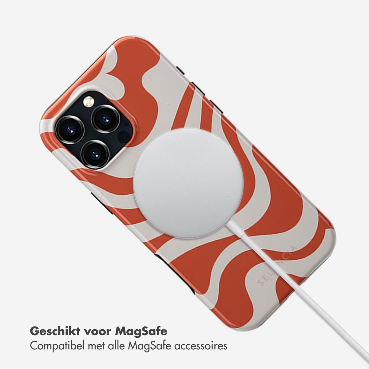 Un iPhone avec un chargeur MagSafe attaché. Le téléphone a un étui à motifs rouges et blancs. Un chargeur blanc est connecté.