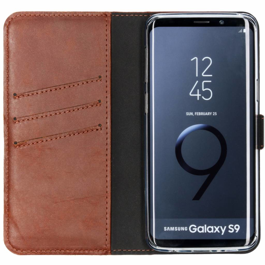 Een bruine leren telefoonhoes met een Samsung Galaxy S9 telefoon erin, die de tijd en datum weergeeft.
