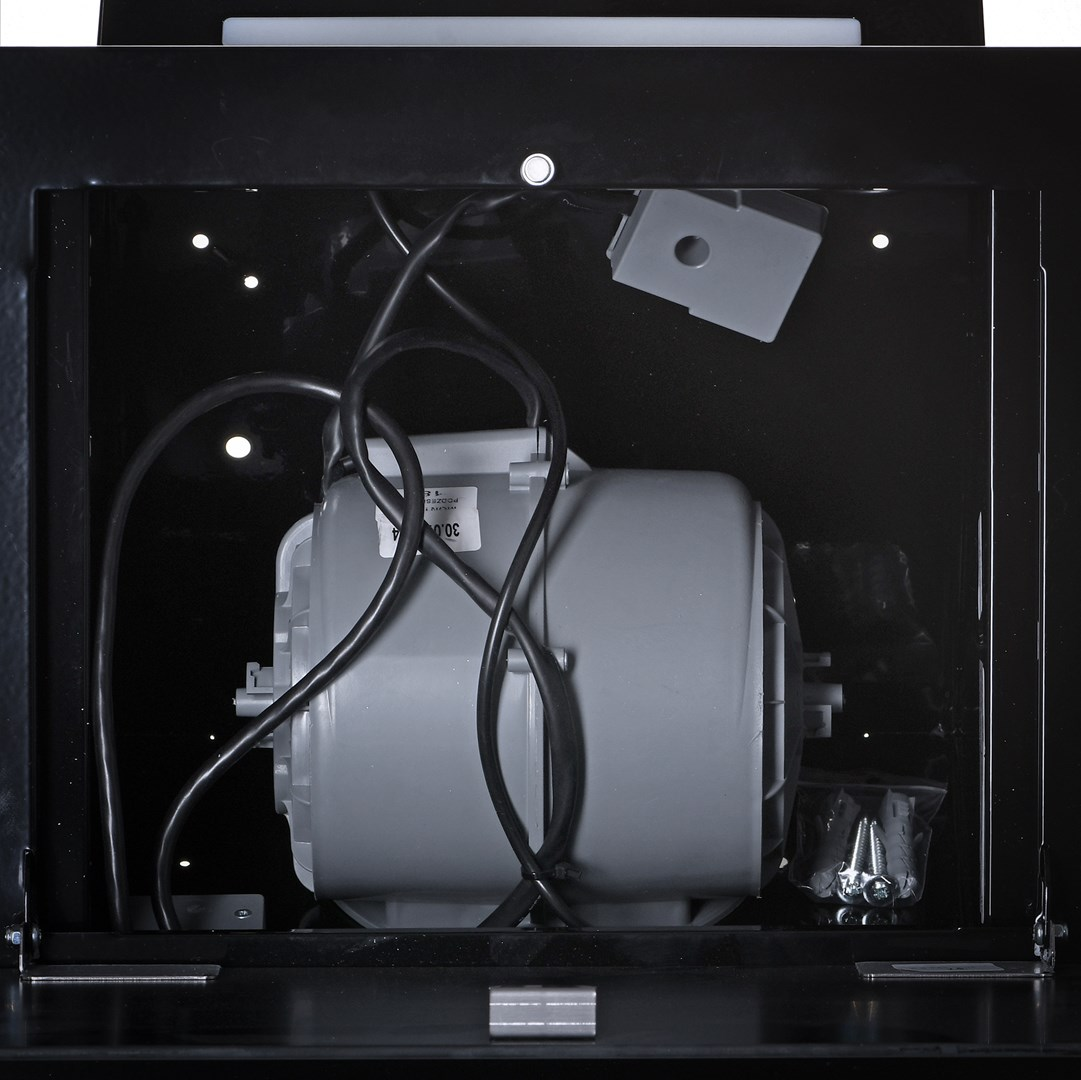 Wnętrze czarnej maszyny. Widoczny jest szary silnik z czarnymi przewodami. W plastikowej torbie znajdują się śruby.