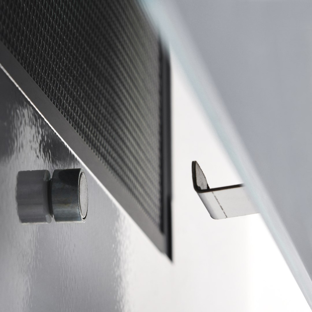 Zbliżenie metalowego otworu wentylacyjnego z uchwytem magnetycznym. Otwór jest czarny, ze srebrną ramą. Metalowy uchwyt po lewej stronie.