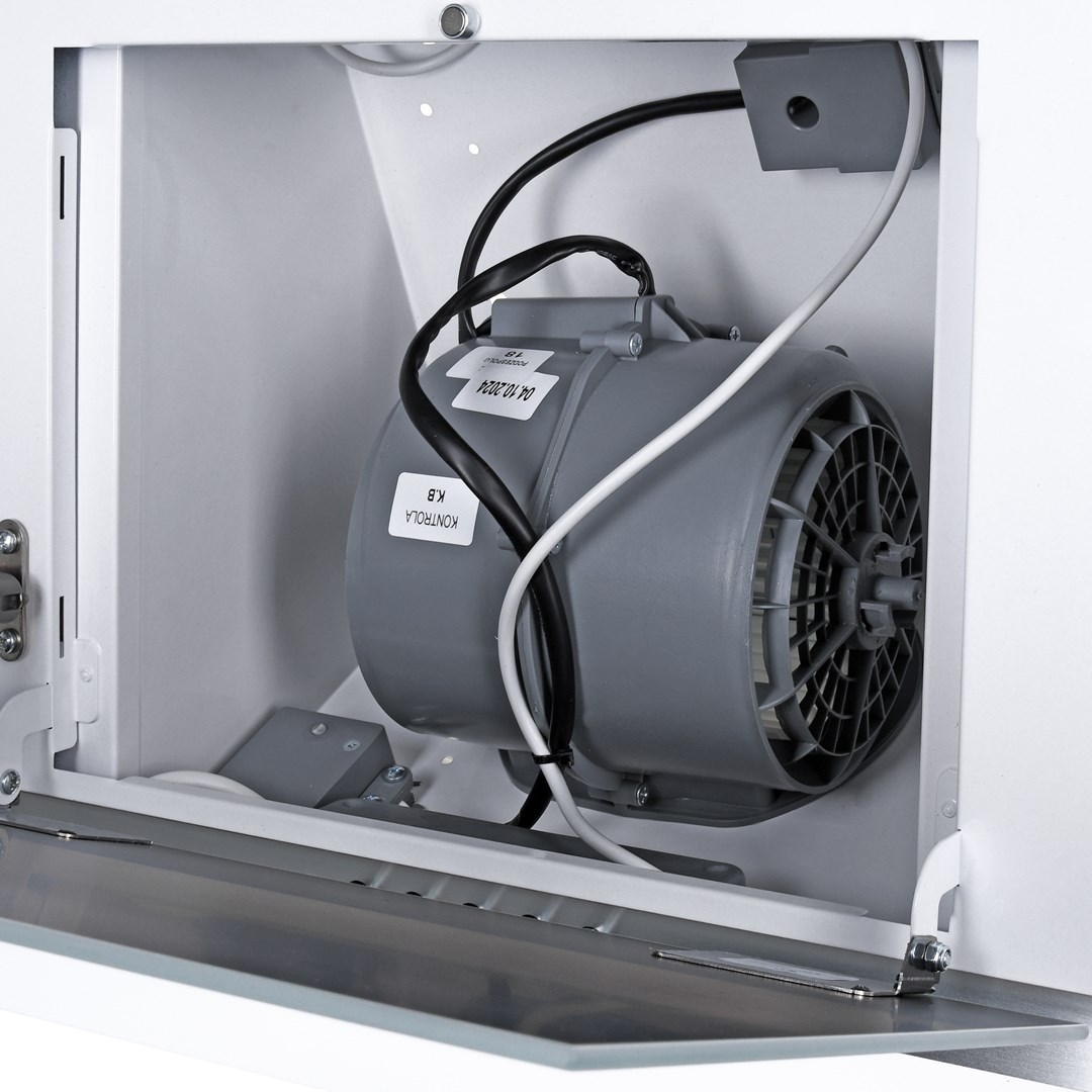 W białej szafce szary silnik z wentylatorem i przewodami. Etykieta na silniku mówi 'KONTROLA K.B.' i datę. Drzwi są otwarte.