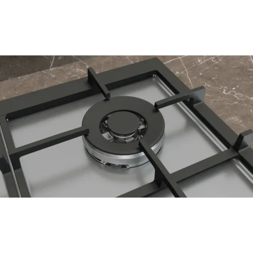 Primer plano de un quemador de gas negro. Superficie plateada, rejillas negras y una encimera de mármol marrón al fondo.