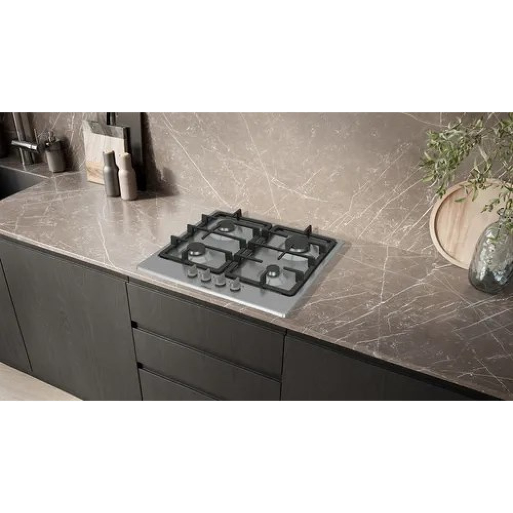 Nowoczesna kuchnia z płytą grzewczą na środku. Blat jest marmurowy, pod spodem ciemne szafki. Inne przedmioty są na blacie.