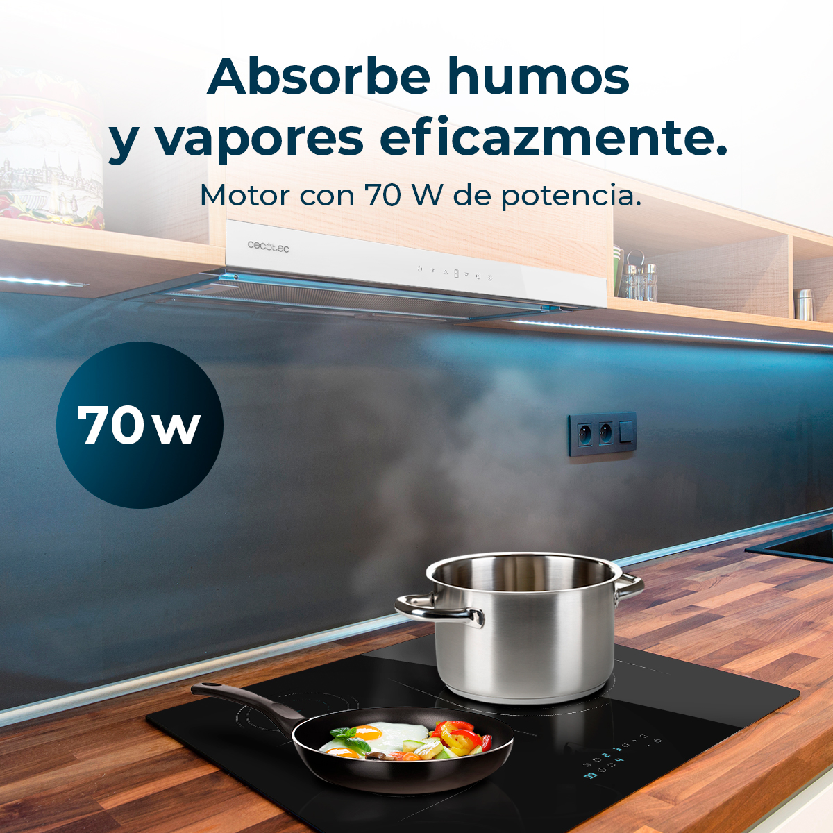 Cocina con vitrocerámica negra, sartén con huevo frito y verduras, olla de acero y campana extractora. Texto indica 70W.