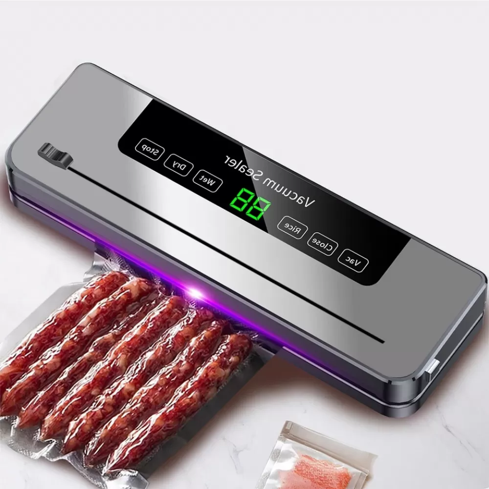 Ein Vakuumiergerät mit Würstchen in einer Tüte. Die Maschine ist grau und hat ein Digitaldisplay. Daneben eine weitere Tüte mit Essen.