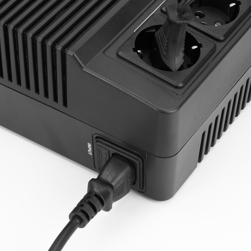Black UPS with power outlets and an input plug. The device is on a white surface. The image is a close-up.