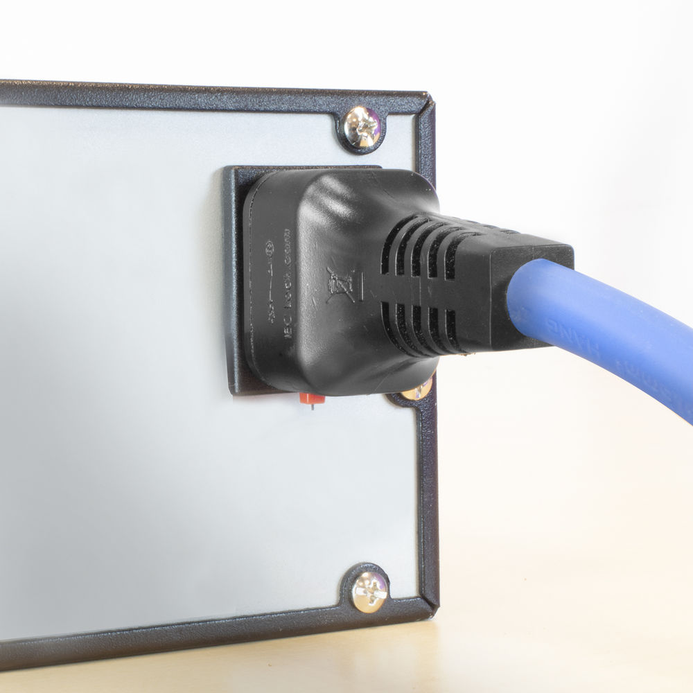 Ein schwarzes Netzkabel ist in ein Panel eingesteckt. Das Panel ist grau mit schwarzem Rahmen. Schrauben sind sichtbar.