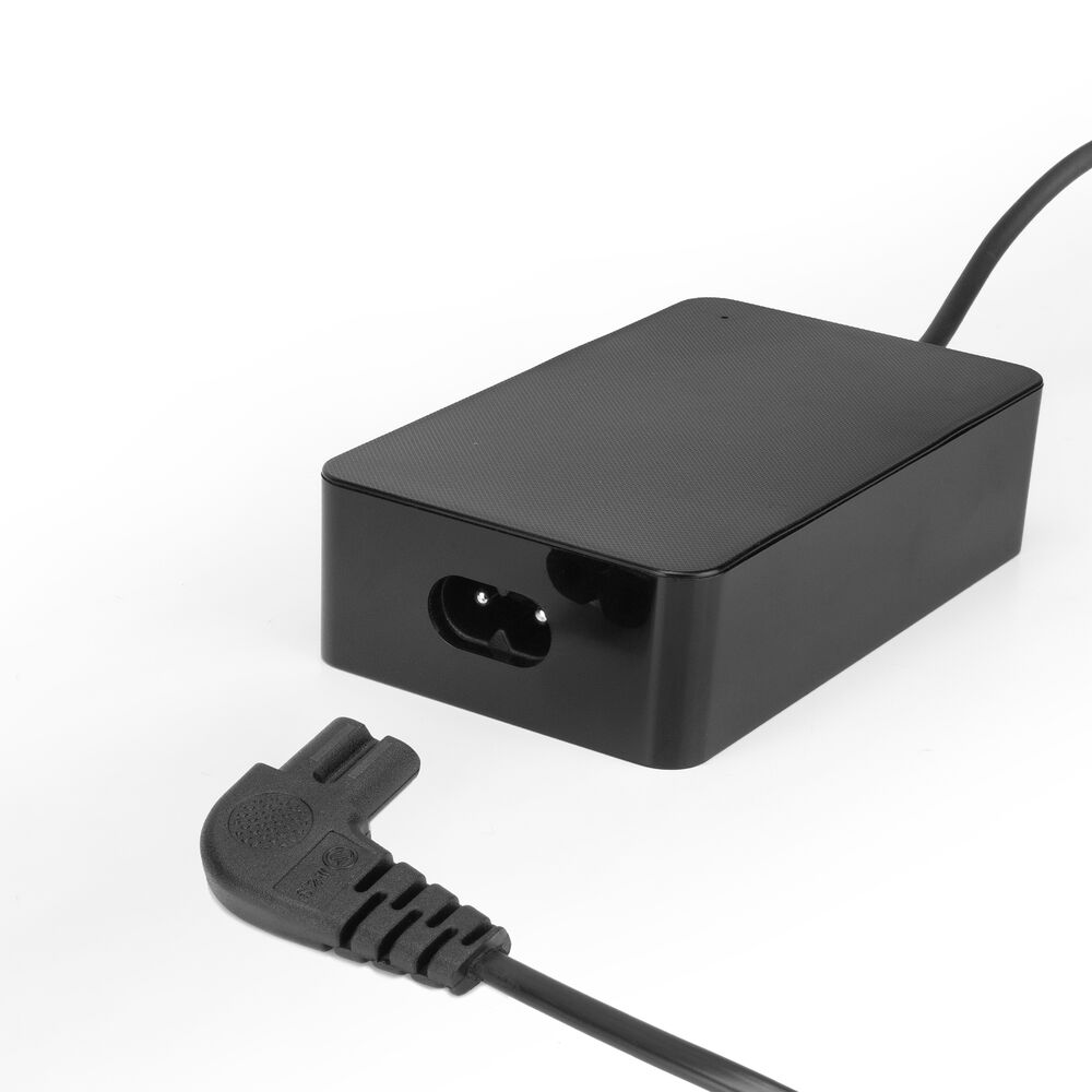 Ein schwarzes Netzteil mit einem dreipoligen Stecker und einer zweipoligen Buchse. Der Adapter befindet sich auf einer weißen Oberfläche.