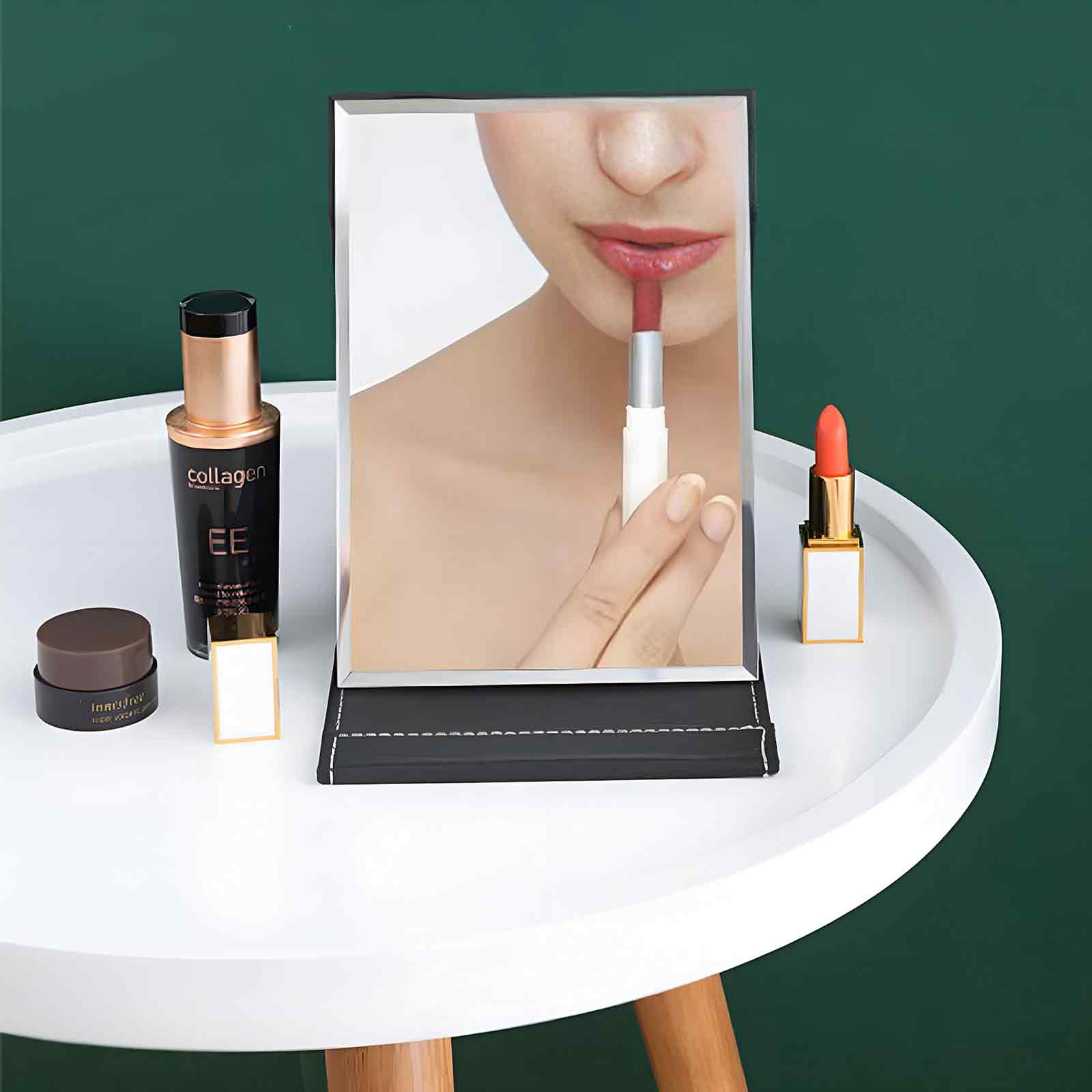 Ein Spiegel reflektiert eine Person, die Lippenstift aufträgt. Make-up-Artikel und ein Hautpflegeprodukt stehen auf einem weißen Tisch.