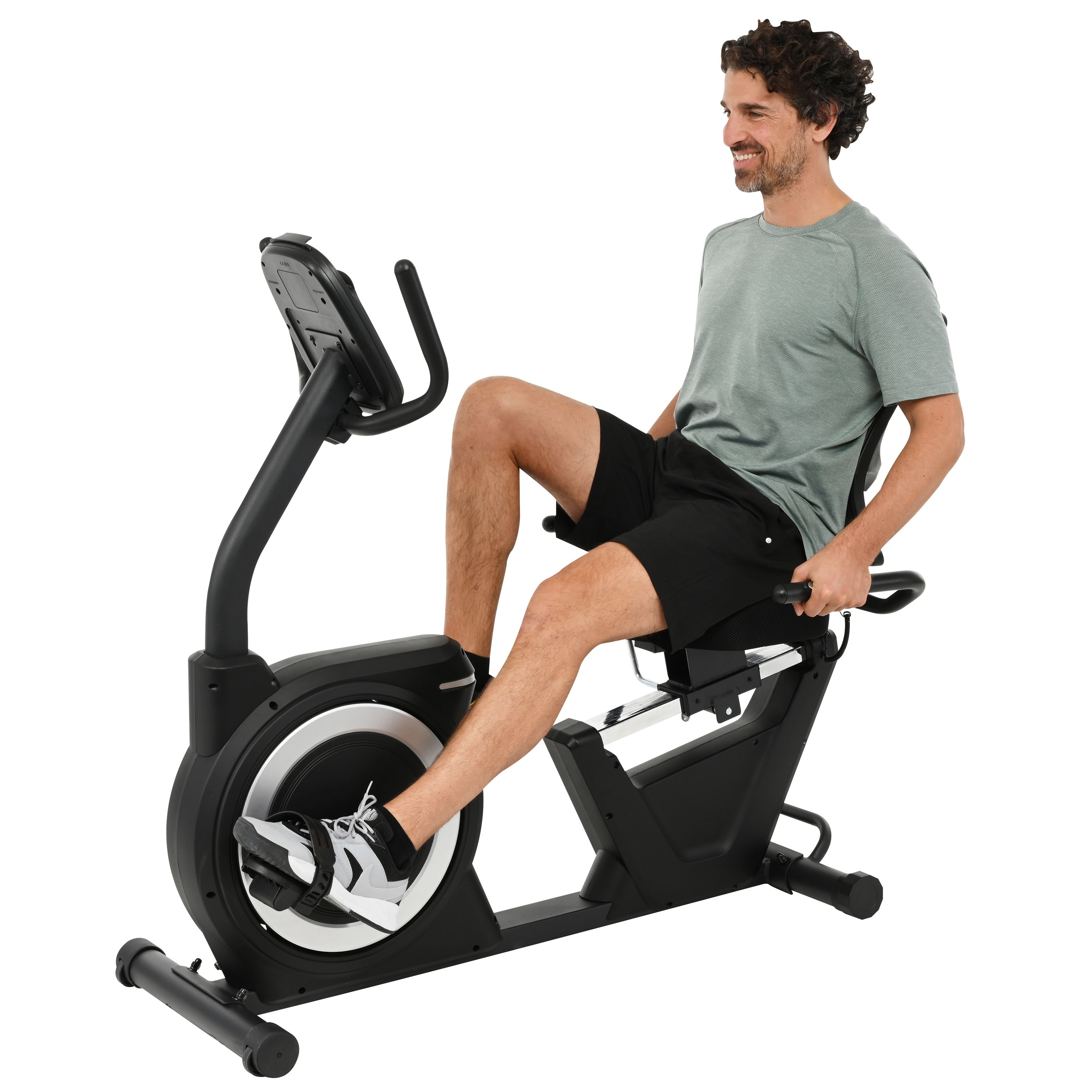 Ein Mann fährt auf einem stationären Fahrrad. Er trägt ein graues Hemd und schwarze Shorts. Das Fahrrad ist schwarz und silber.