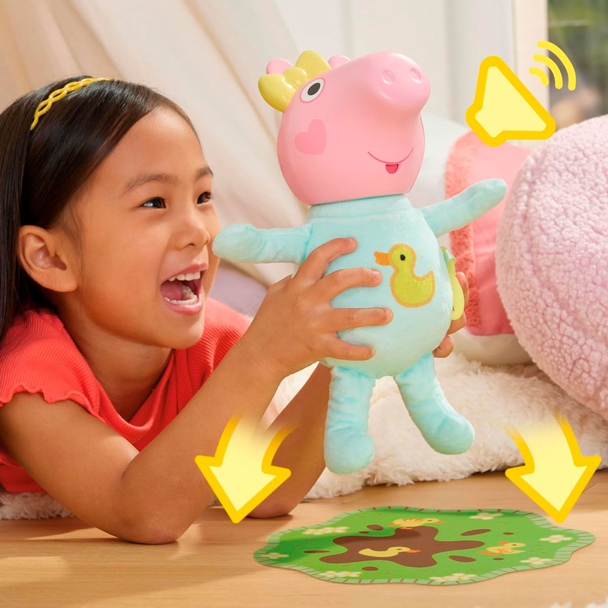 Ein Mädchen hält ein Peppa Wutz-Spielzeug und lächelt. Pfeile zeigen auf eine schlammige Pfützenmatte. Ein Lautsprechersymbol ist sichtbar.