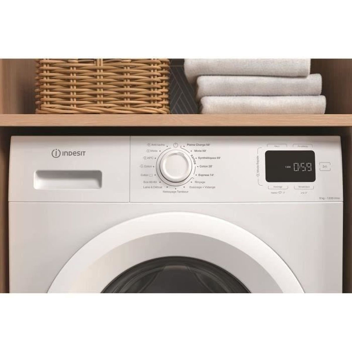 Eine weiße Indesit-Waschmaschine mit digitaler Anzeige 0:59. Oben befinden sich ein Weidenkorb und gefaltete weiße Handtücher.