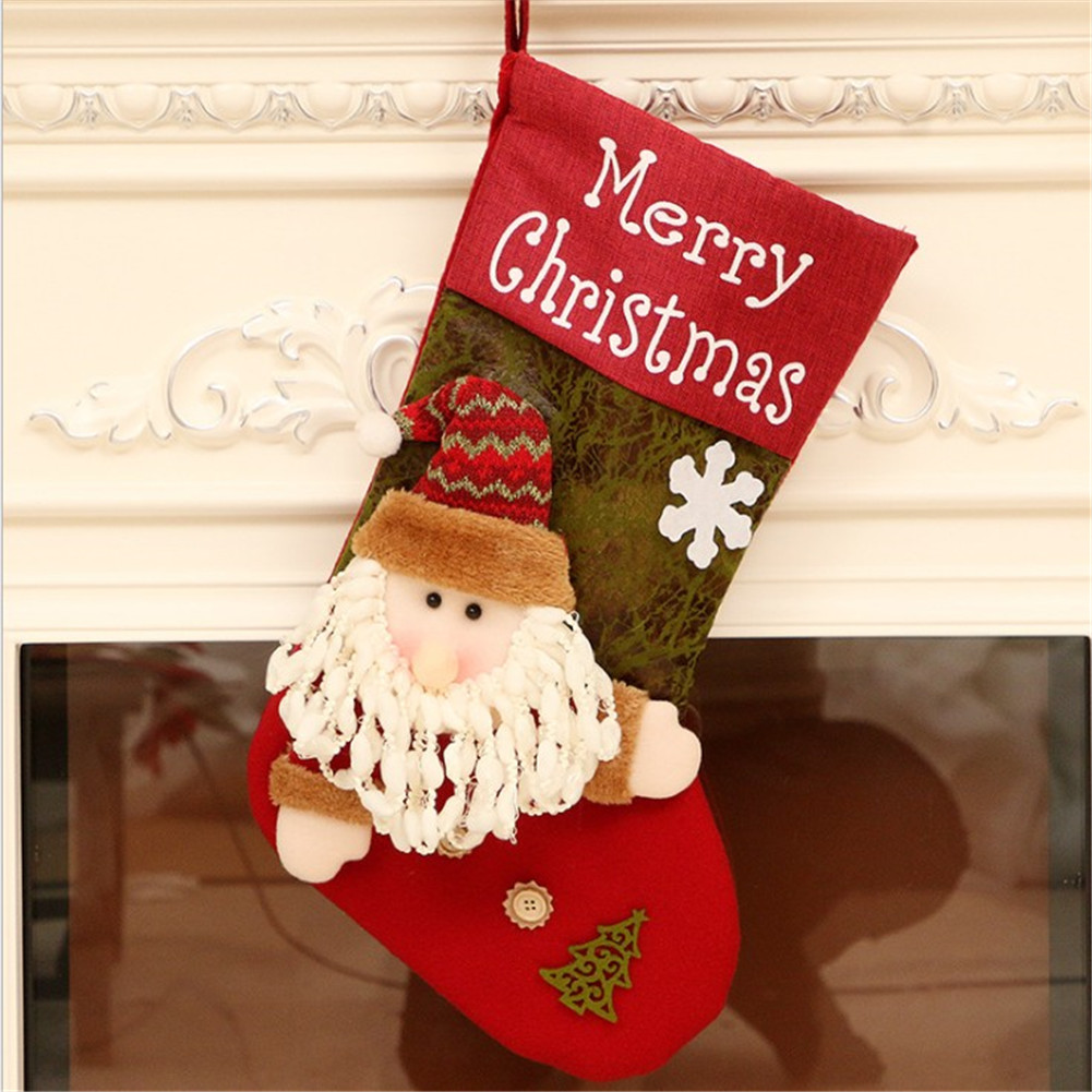 Ein Weihnachtsstrumpf mit Santa Claus-Design, rot und grün. Frohe Weihnachten Text. Es hängt vor weißem Hintergrund.
