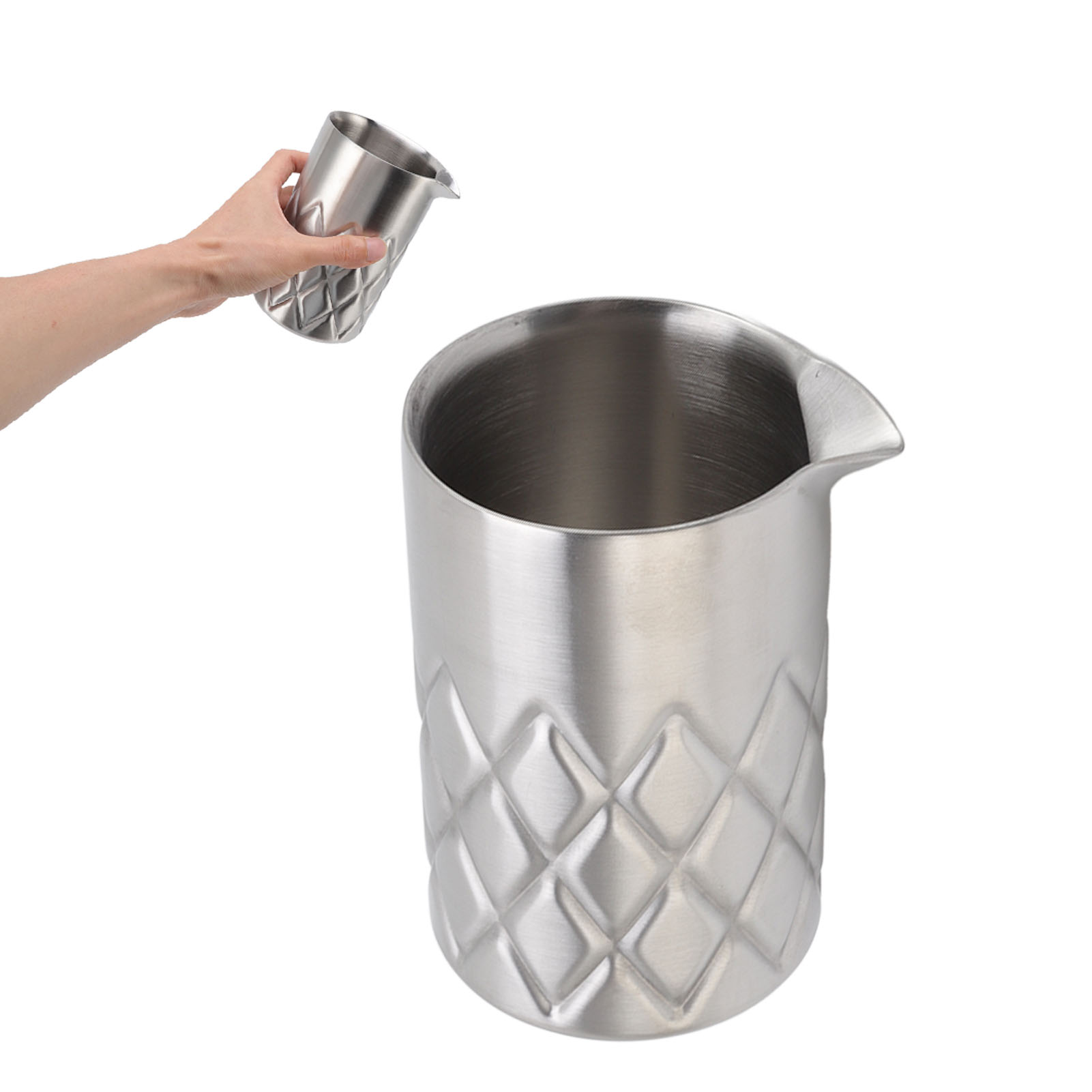 Eine Hand hält einen silbernen Cocktailshaker. Daneben steht ein größerer Shaker. Beide sind rautenförmig gemustert.