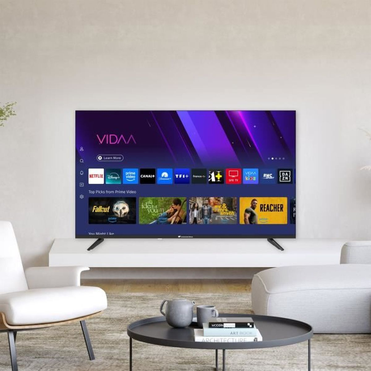 Ein modernes Wohnzimmer mit einem Fernseher, der Streaming-Apps anzeigt. Ein weißes Sofa und ein Stuhl befinden sich im Raum, mit einem schwarzen Couchtisch.