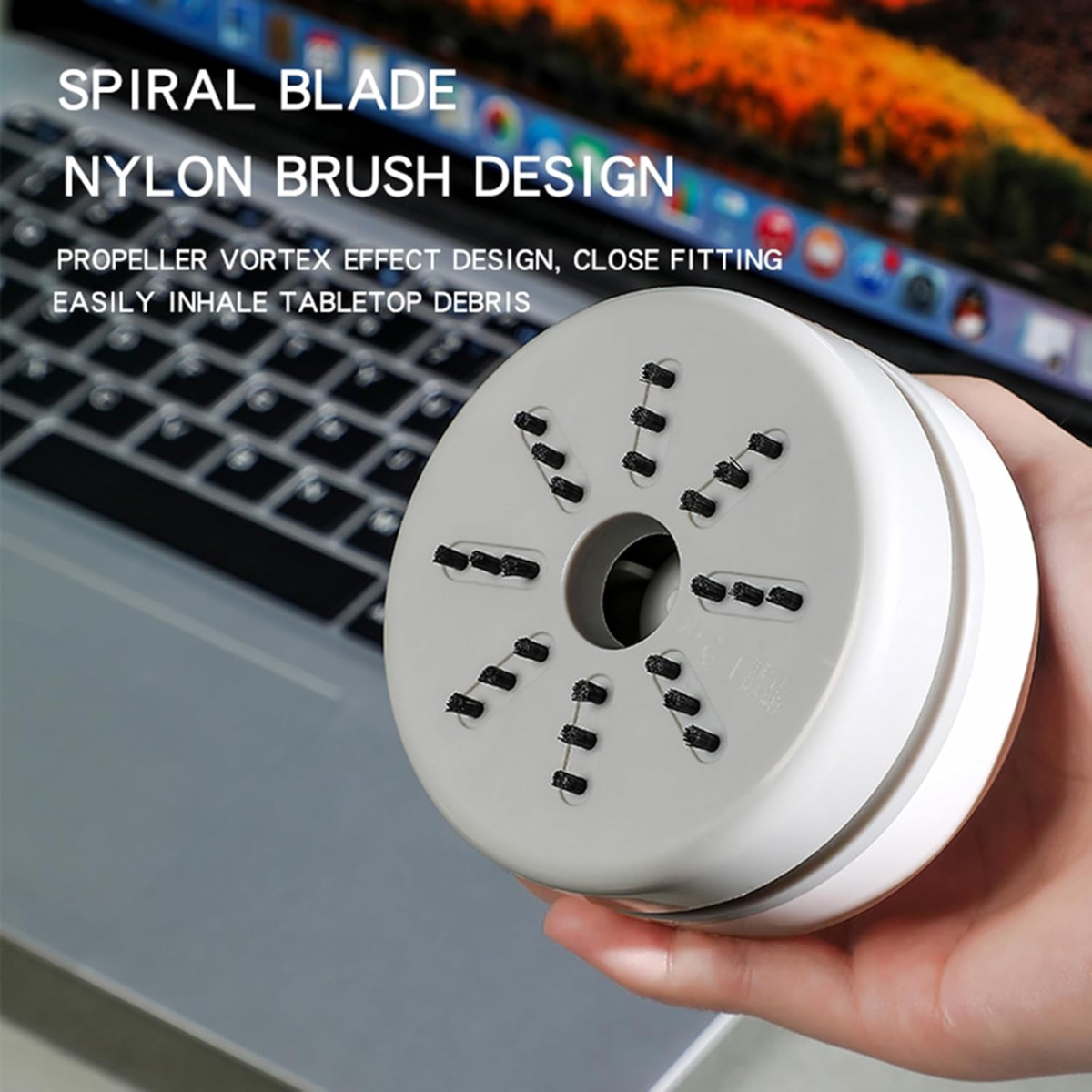 Ein tragbarer weiß-grauer Staubsauger mit Nylonbürsten wird über einer Laptop-Tastatur gehalten, Produktaufnahme.