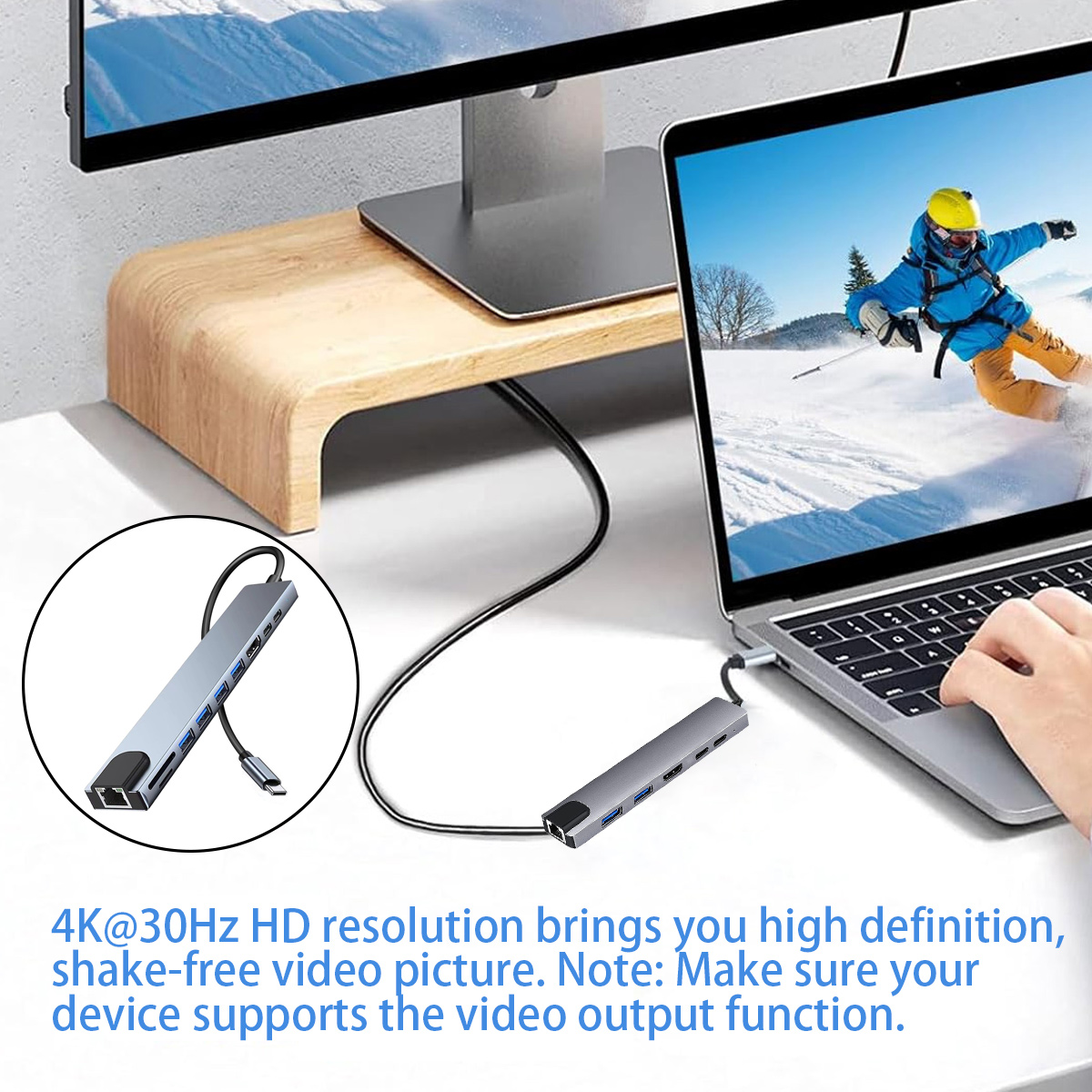 Ein Laptop ist mit einem Hub verbunden. Auf dem Bildschirm ist ein Skifahrer zu sehen. Ein Monitor und ein Holzständer befinden sich im Hintergrund.