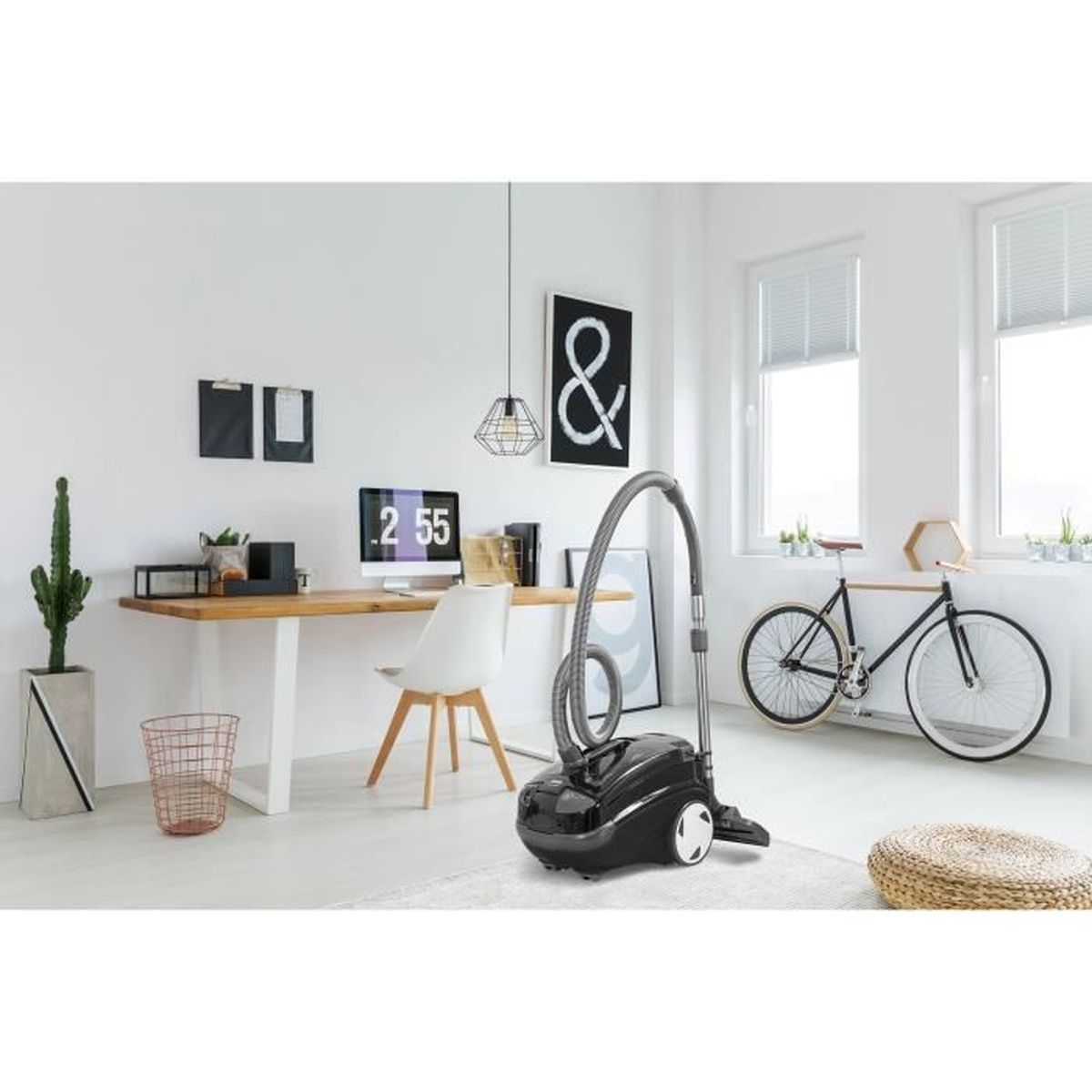 Zimmer mit Schreibtisch, Computer, Staubsauger, Fahrrad und Dekoration. Die Wände sind weiß. Der Boden ist hell.