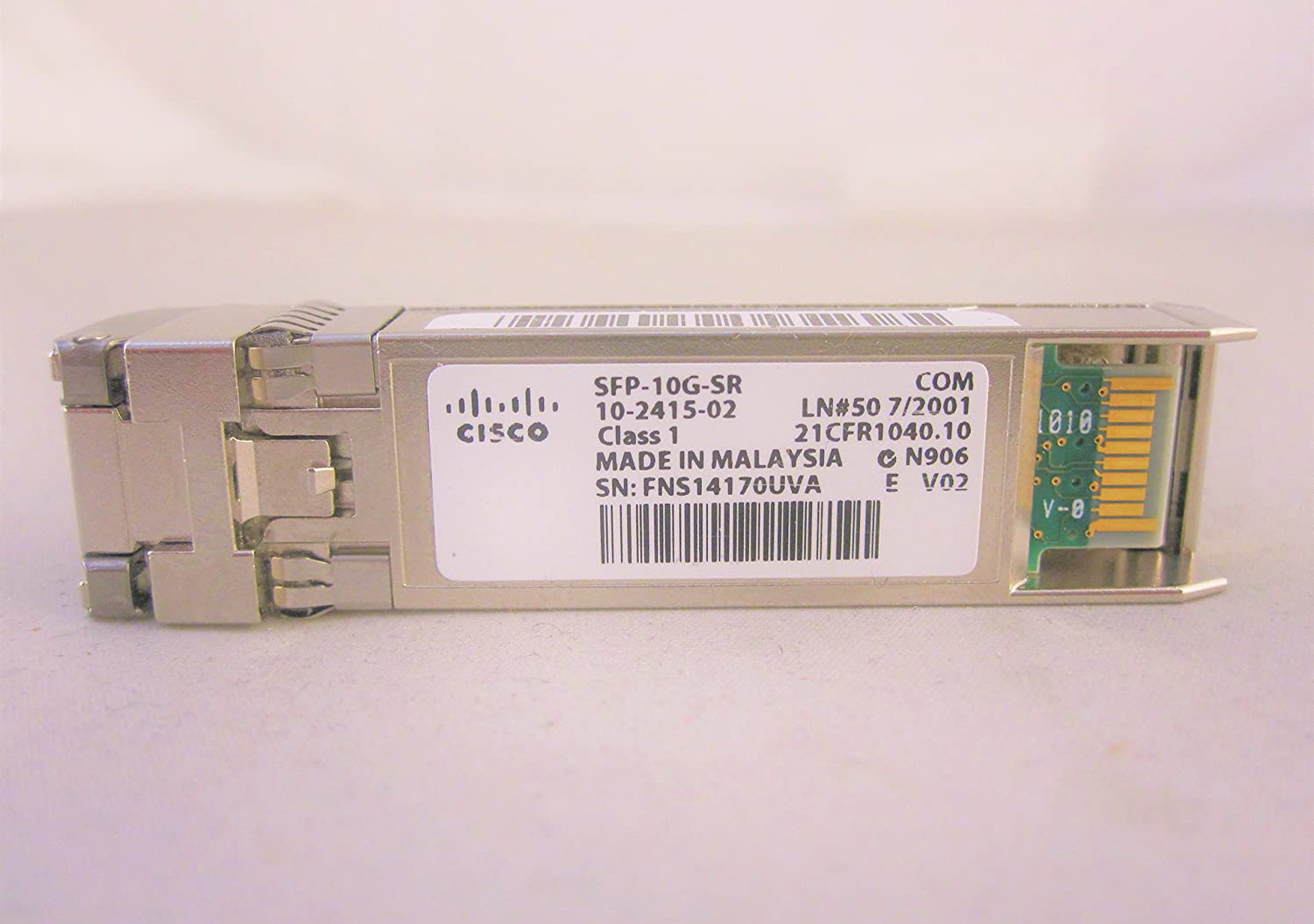 Ein silbernes Cisco SFP-10G-SR-Modul. Es hat ein weißes Etikett mit Text und eine grüne Platine.