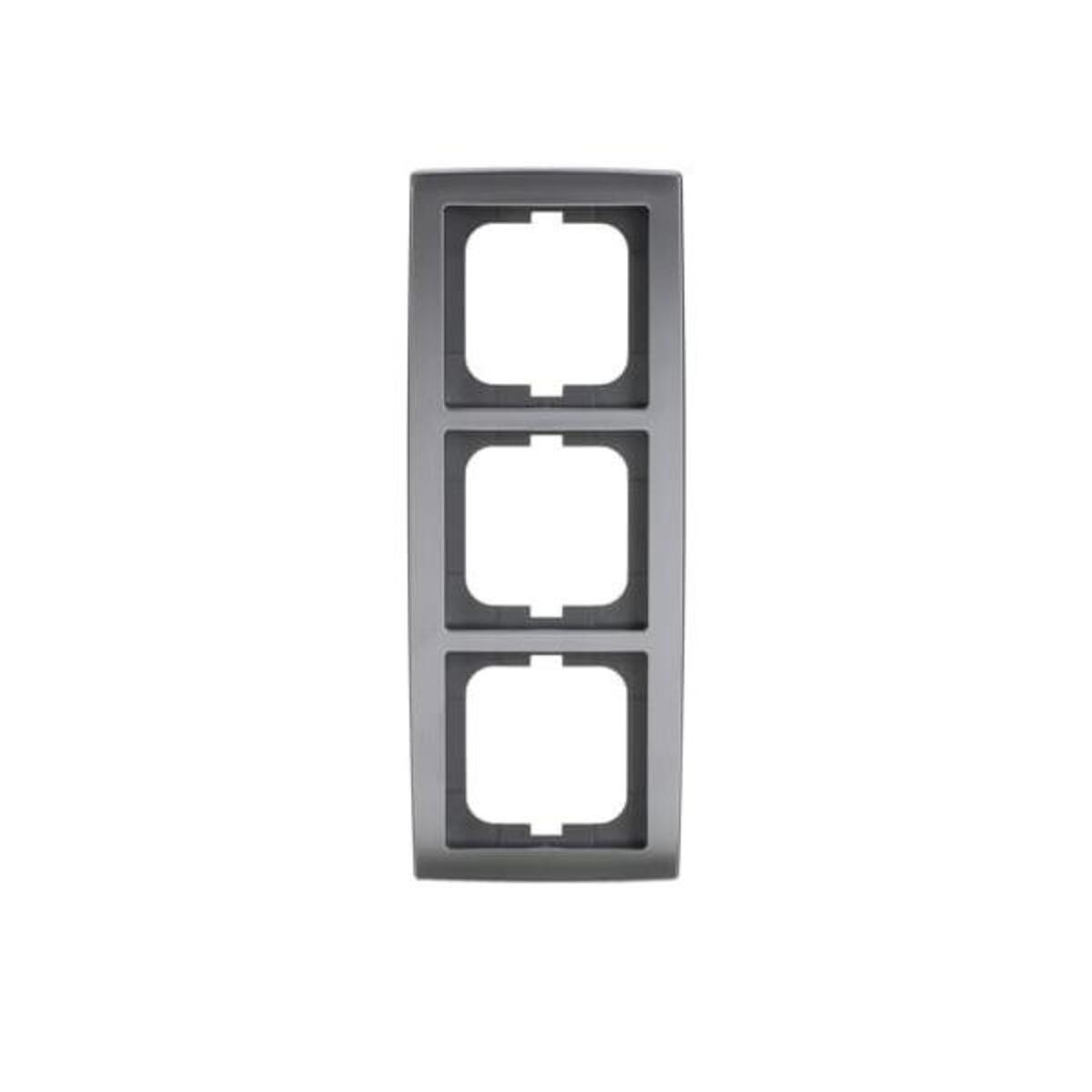 Un telaio grigio per prese elettriche con tre aperture quadrate. Il telaio è rettangolare con angoli arrotondati, su sfondo bianco.