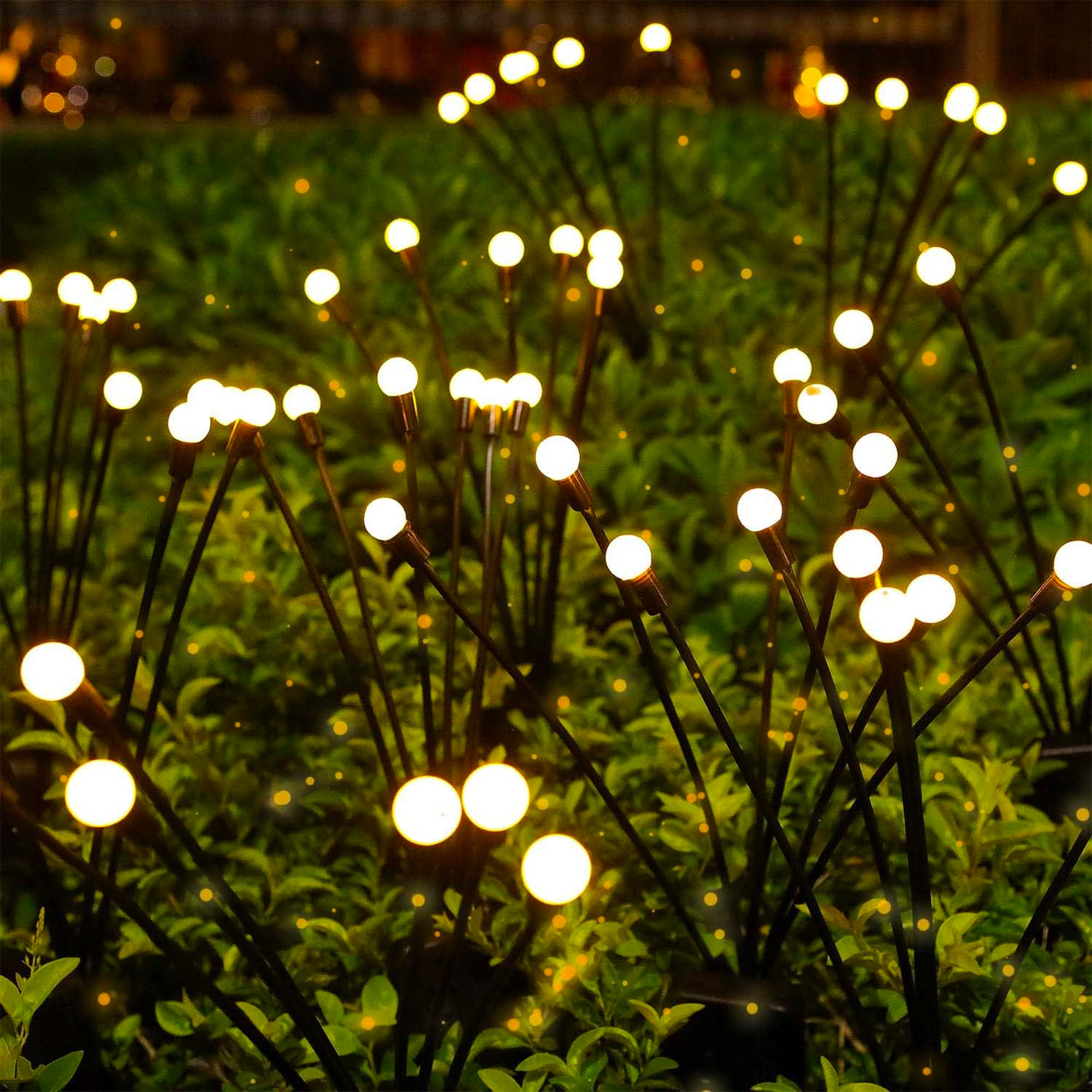 Dekorative Lichter mit weißen Kugeln auf dunklen Stielen in einem grünen Busch. Der Hintergrund hat verschwommene Lichter.