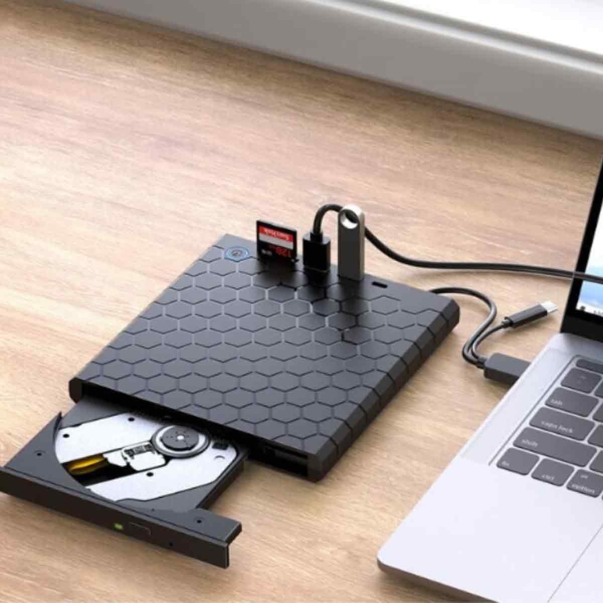 Ein schwarzes externes CD-Laufwerk mit SD-Kartensteckplatz, das mit einem Laptop verbunden ist. Das Laufwerk ist geöffnet und zeigt eine CD im Inneren.