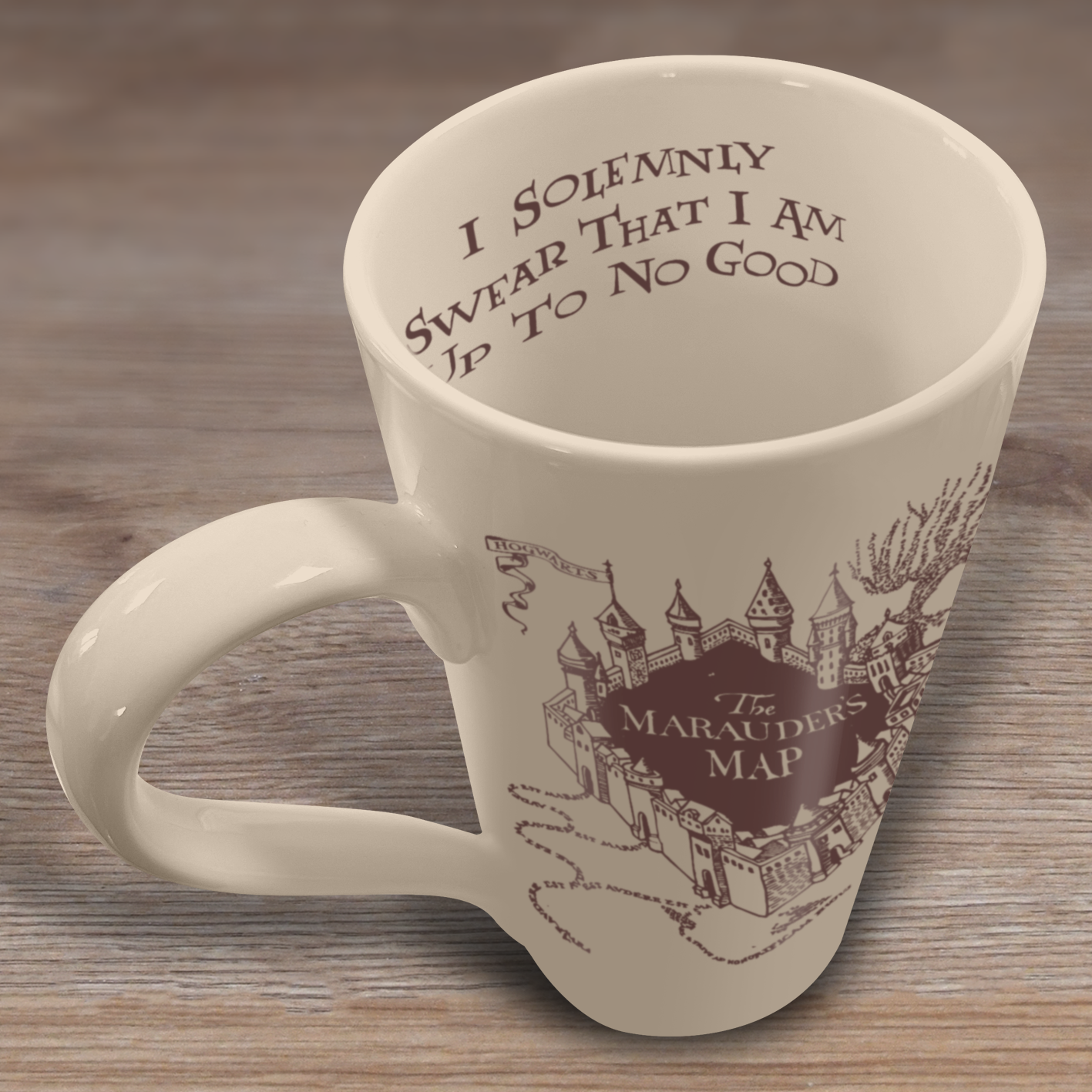 Eine cremefarbene Tasse mit Henkel. Sie hat "Ich schwöre feierlich, dass ich es nicht gut meine" und ein Kartendesign auf der Seite, auf einem Holztisch.