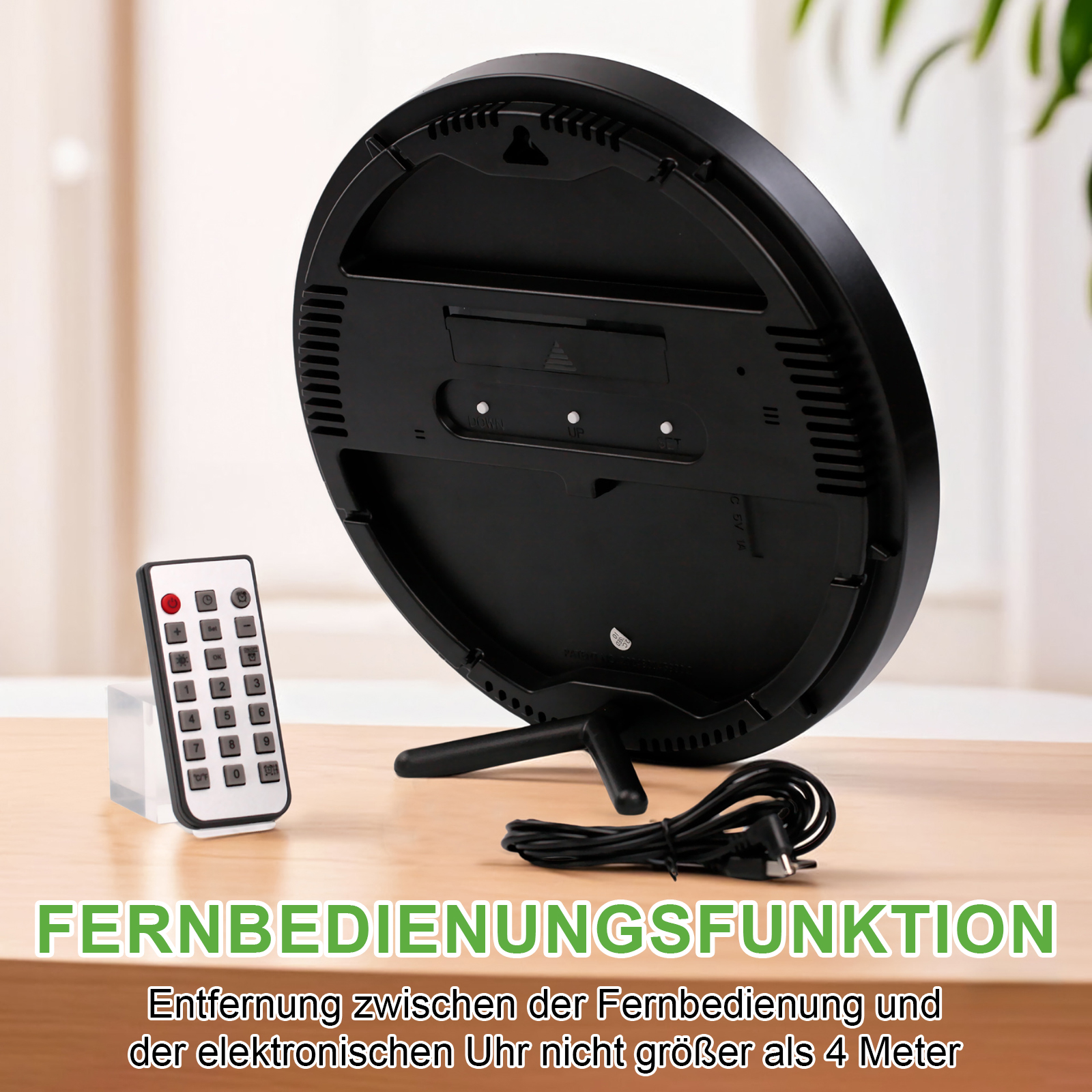 Retro di un orologio nero con supporto, telecomando e cavo di alimentazione su un tavolo di legno. Testo in tedesco.