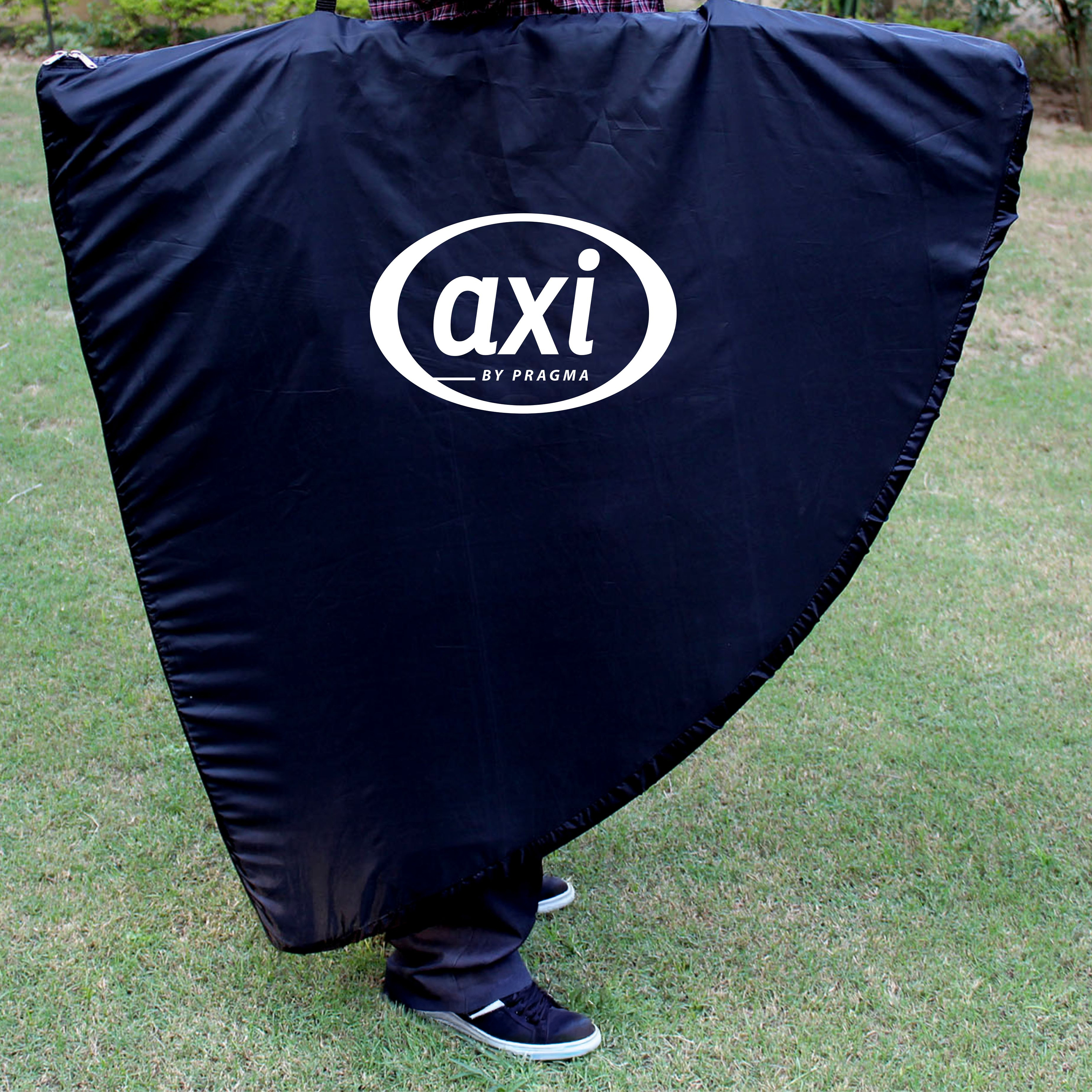 Eine Person hält eine große schwarze Abdeckung mit weißem 'axi'-Logo auf Gras. Die Person trägt schwarze Hosen und Schuhe.