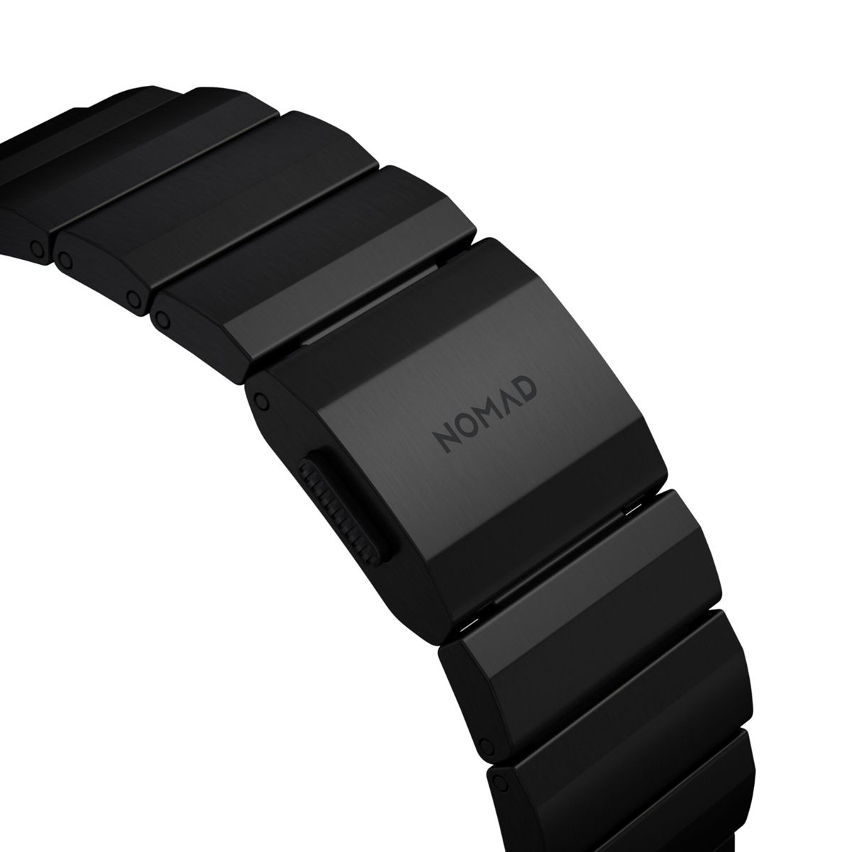 Primo piano di un cinturino nero. La chiusura recita 'NOMAD'. Il cinturino è fatto di maglie rettangolari collegate.