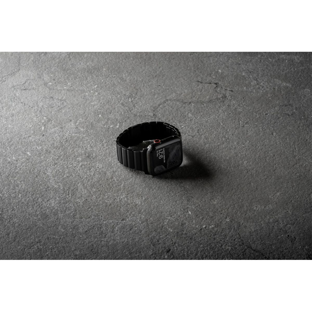 Un Apple Watch nero su una superficie grigia. L'orologio mostra l'ora e ha un cinturino in metallo nero.