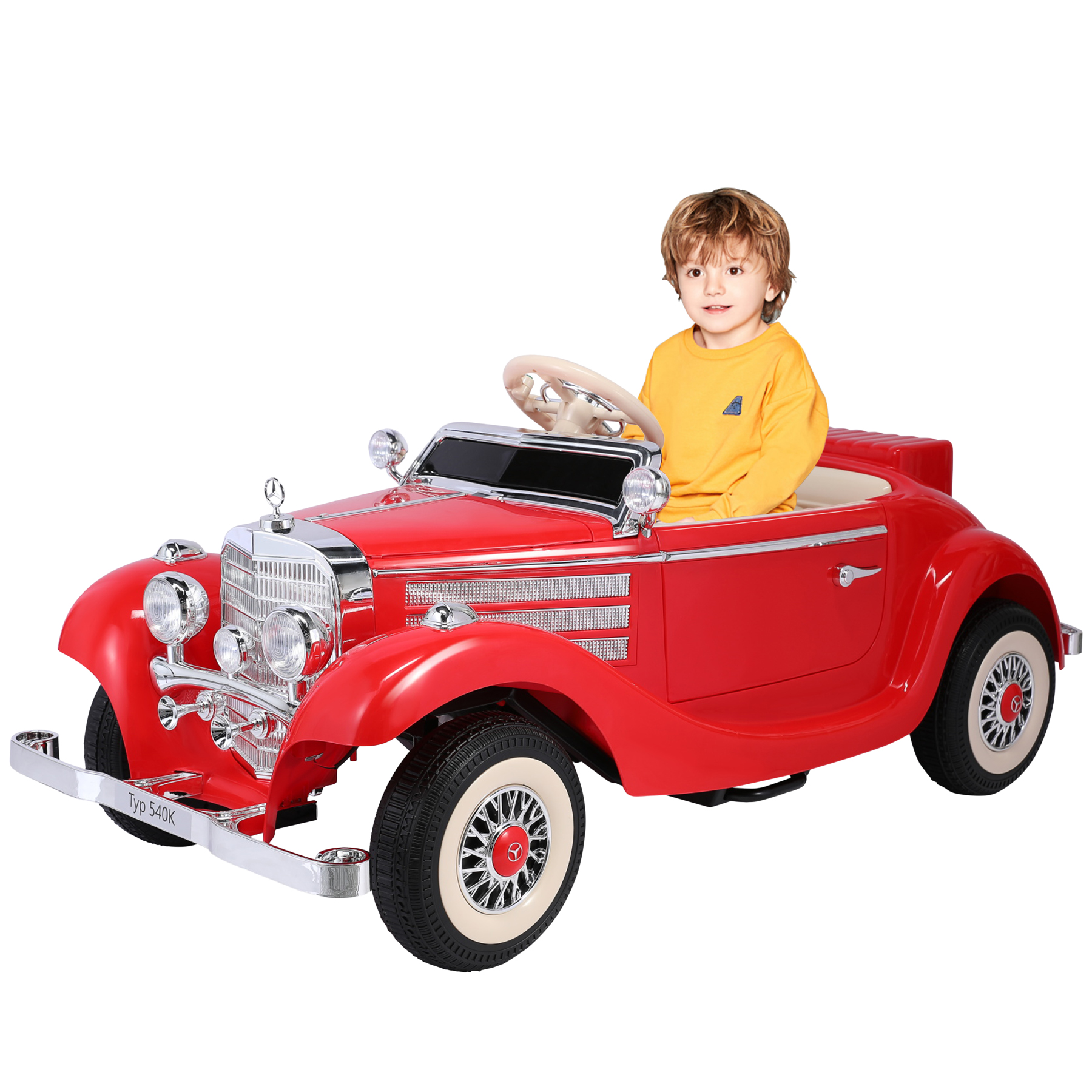 Ein Kind in einem gelben Hemd sitzt in einem roten Spielzeugauto. Das Auto hat Chromdetails und Weißwandreifen auf weißem Grund.