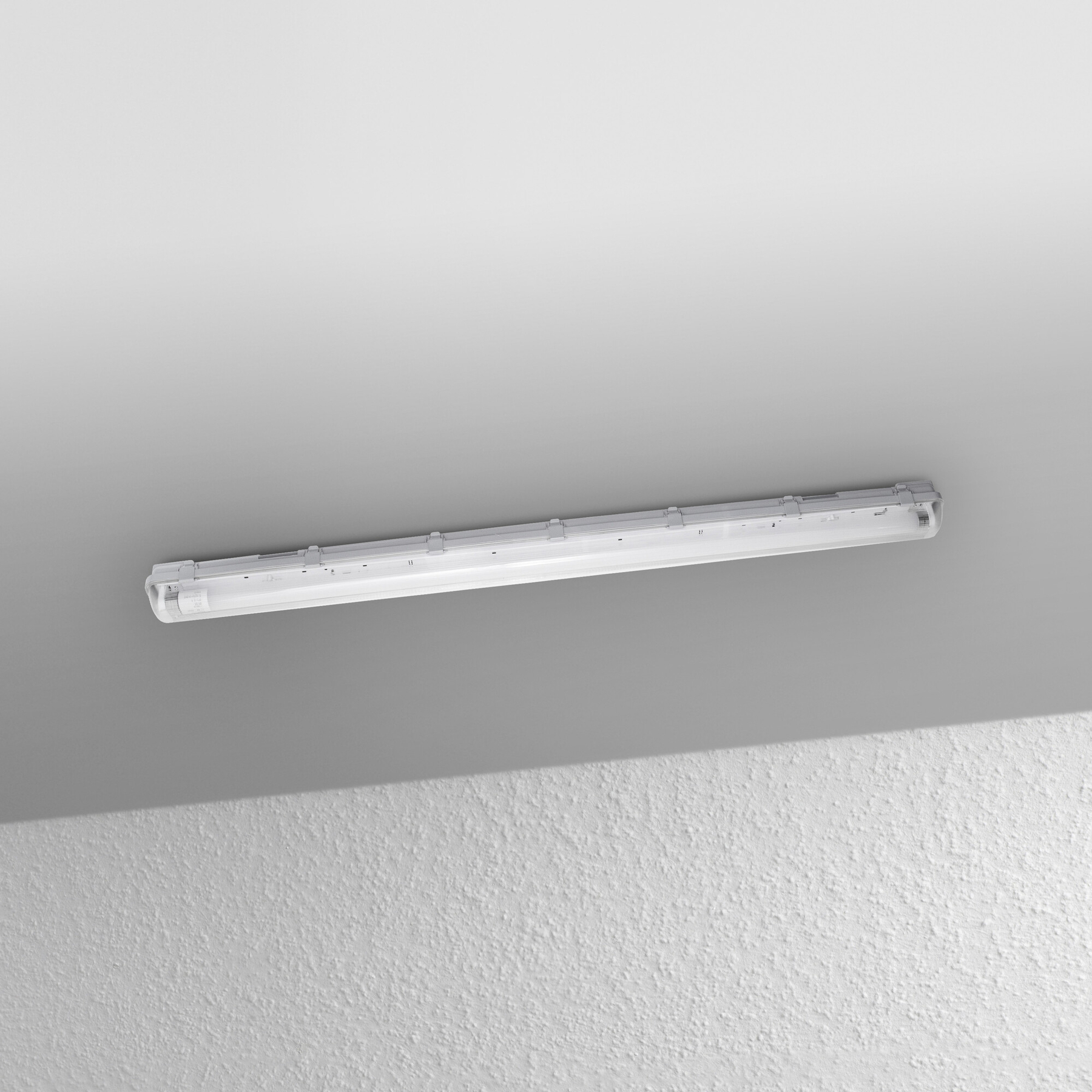 Eine Leuchtstoffröhre ist an der Decke montiert. Die Decke ist weiß, und die Wand darunter hat eine strukturierte Oberfläche.