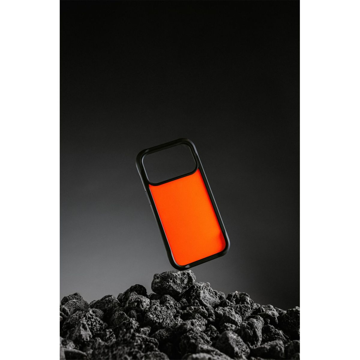 Una custodia arancione con cornice nera fluttua sopra rocce scure su uno sfondo grigio scuro.